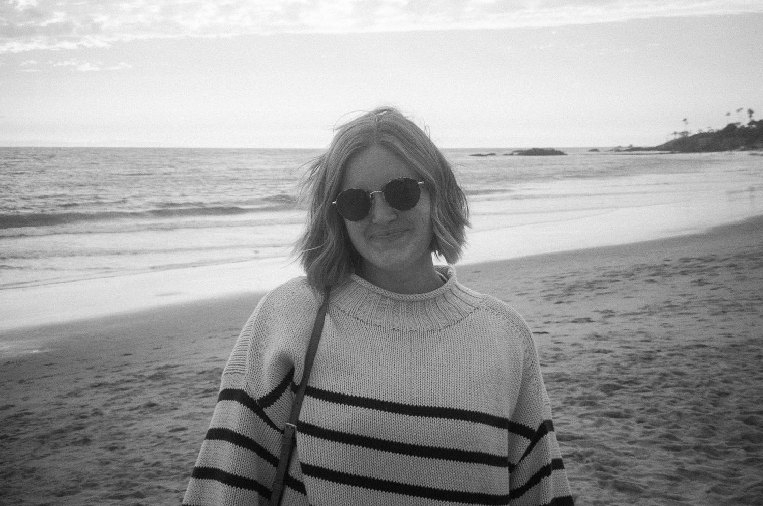 Black and white photos of someone enjoying a sunny day at a scenic beach with waves and rocky coastline in view.