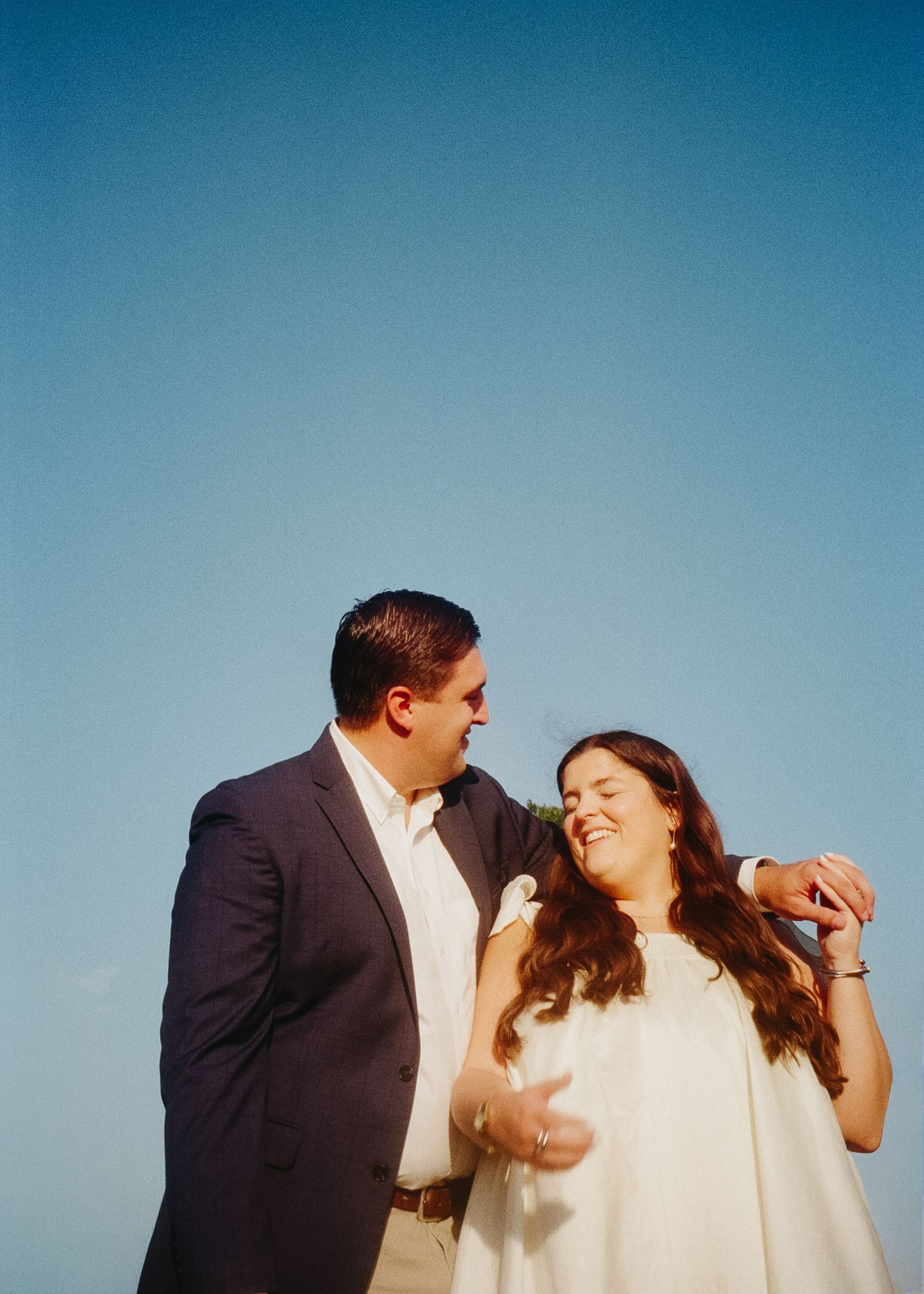 Two people share a playful moment against a bright blue sky background.