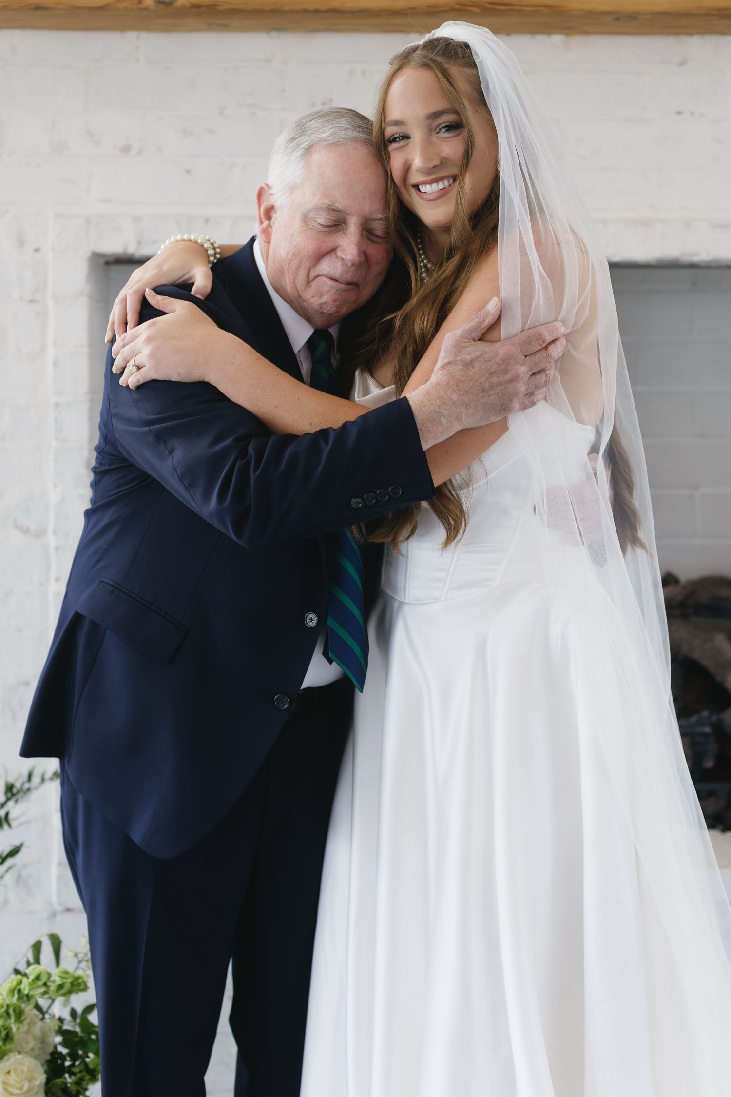 Emotional wedding moment captured under blue and white pottery display.