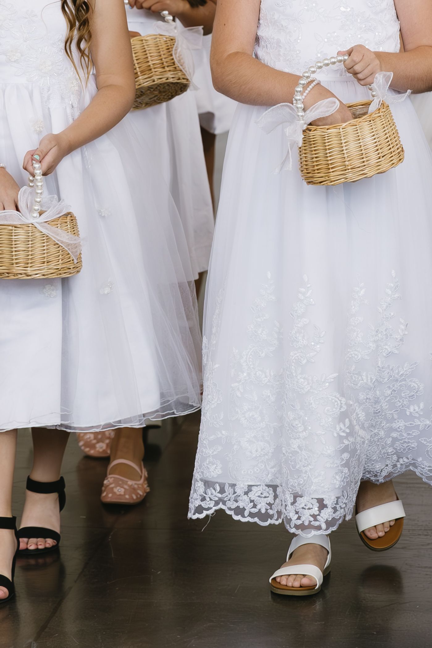 Close-up of wedding dress hemlines and sandals with wicker basket details.