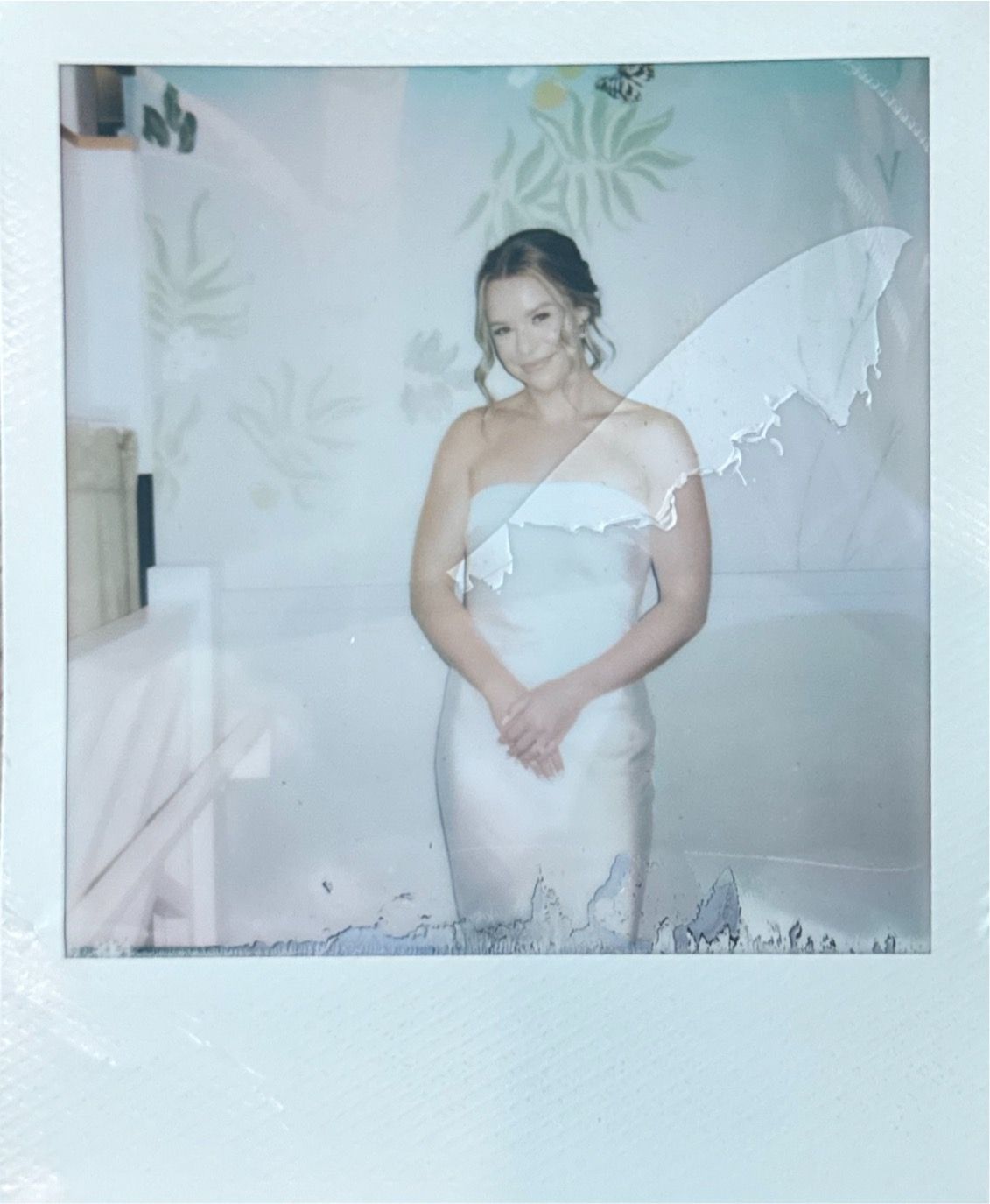 A dreamy boudoir photoshoot with soft lighting and delicate floral wallpaper creates an intimate atmosphere.