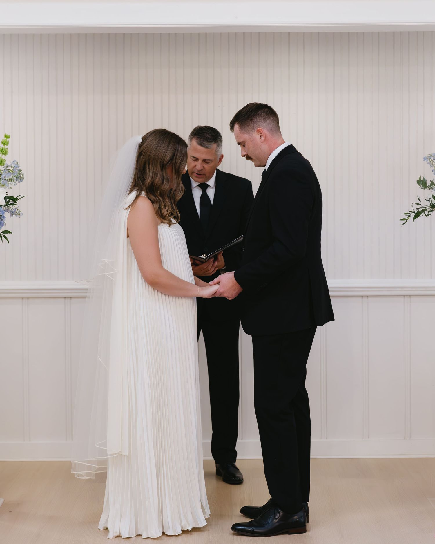 Intimate wedding moments captured in sequence against white paneled walls in bright indoor space.