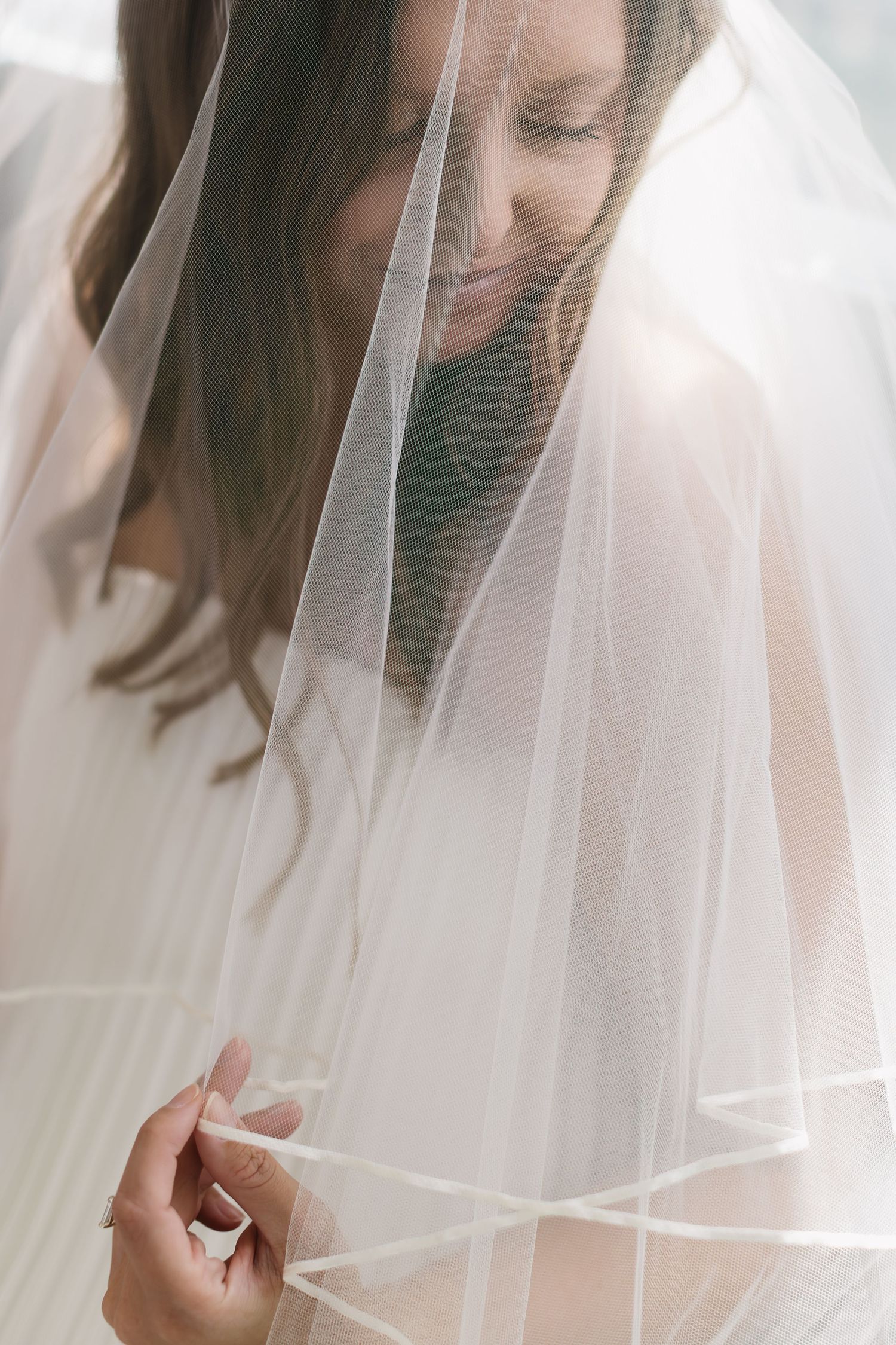 Close-up shot of a delicate white bridal veil with soft natural light filtering through the fabric.