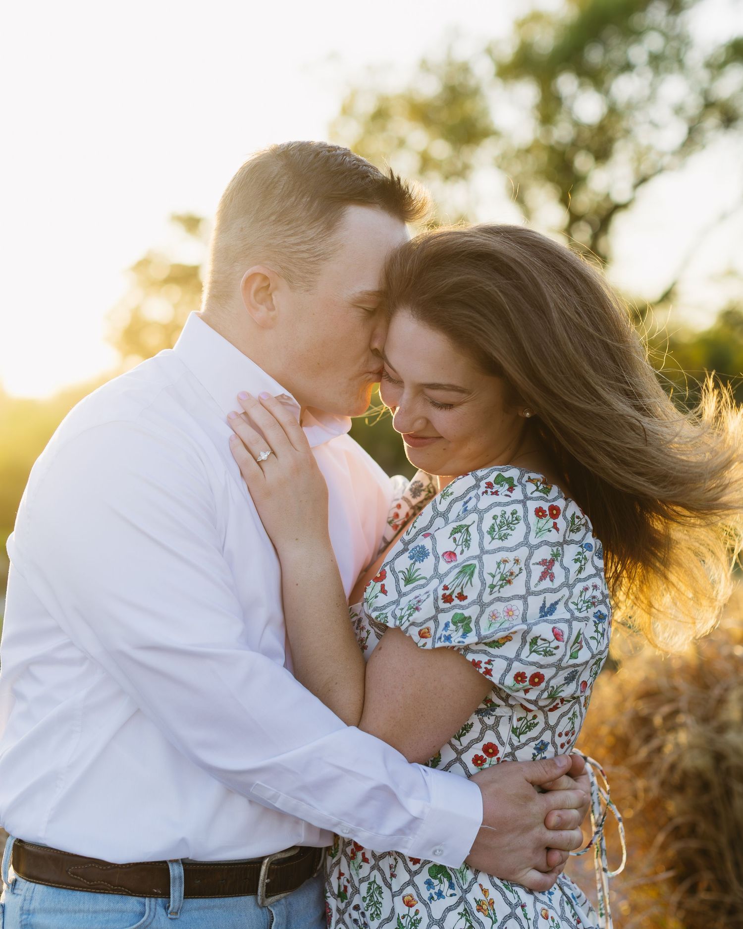 A couple shares intimate moments during a golden hour photoshoot outdoors.