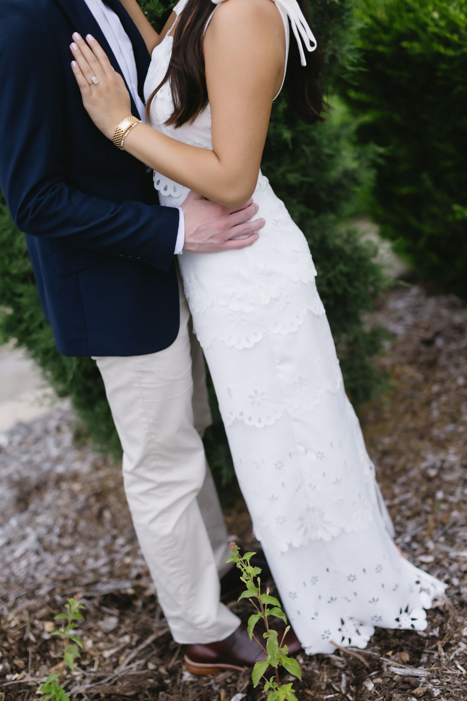 Couple in coordinated white and navy outfits share intimate moment in garden setting.