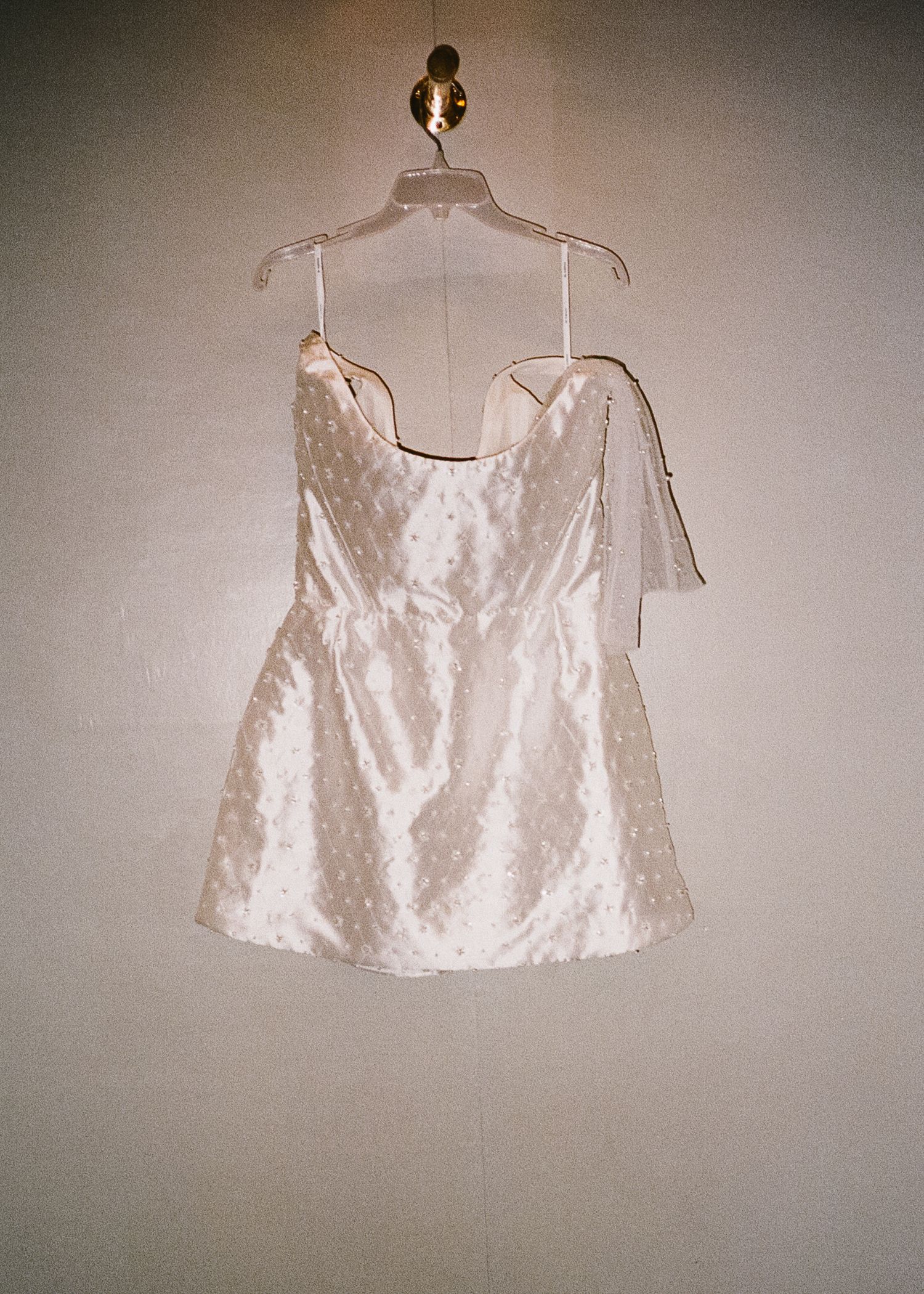White formal garments hanging on display against neutral wall.