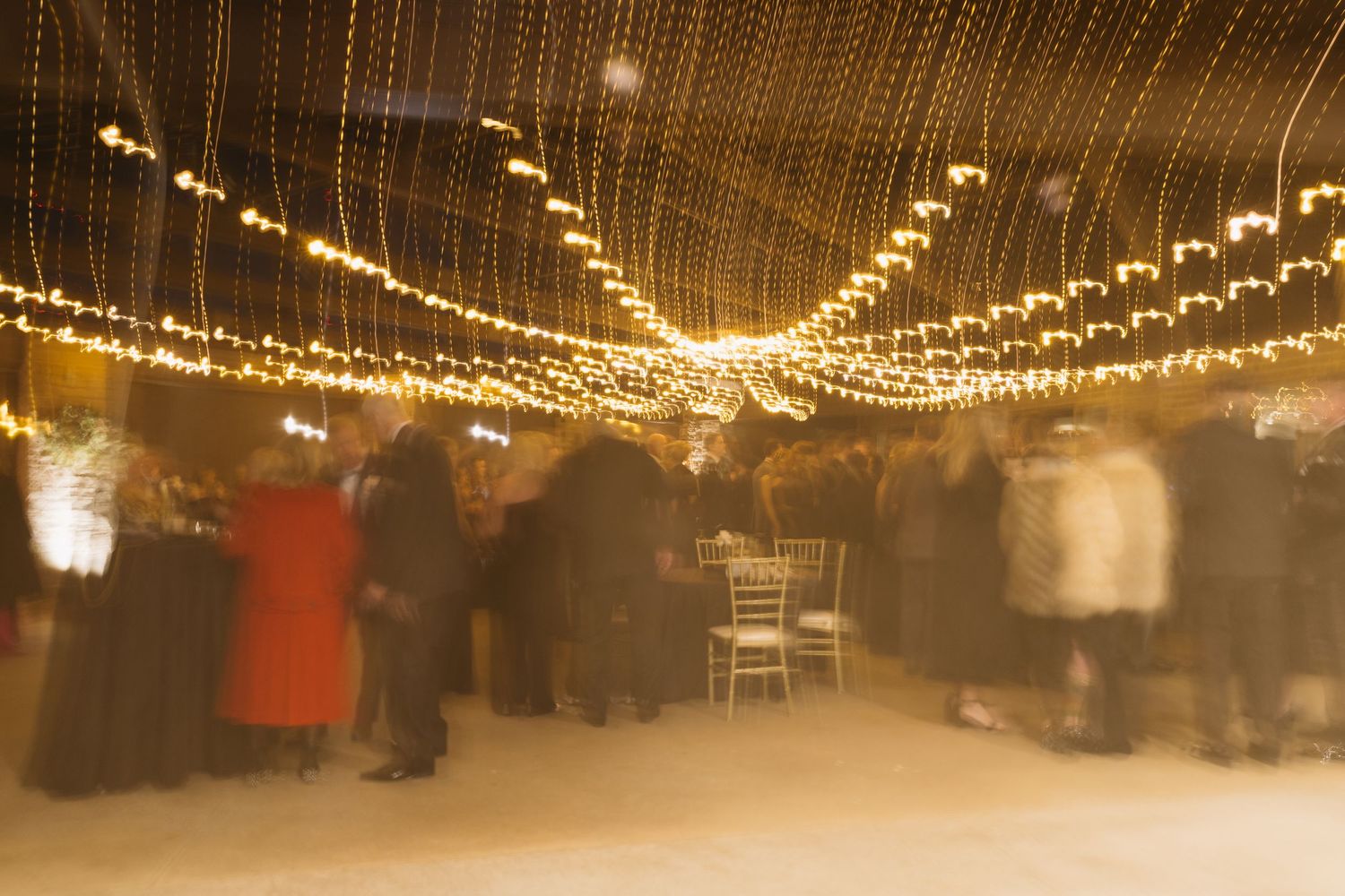 Warm golden string lights create an elegant ceiling display at an evening event.
