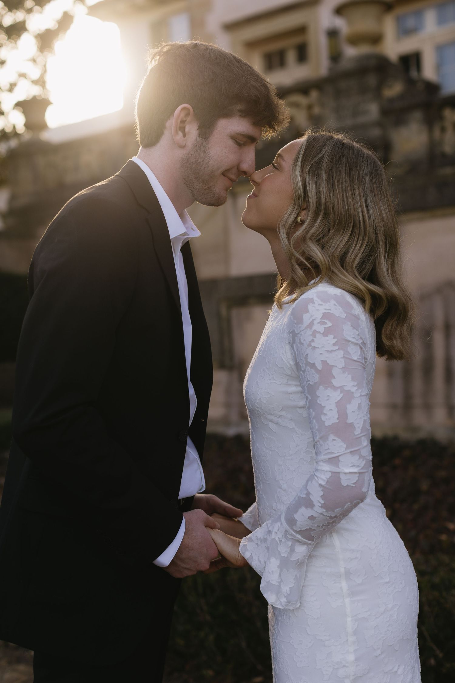 A romantic wedding couple embraces during golden hour in an intimate outdoor portrait session.