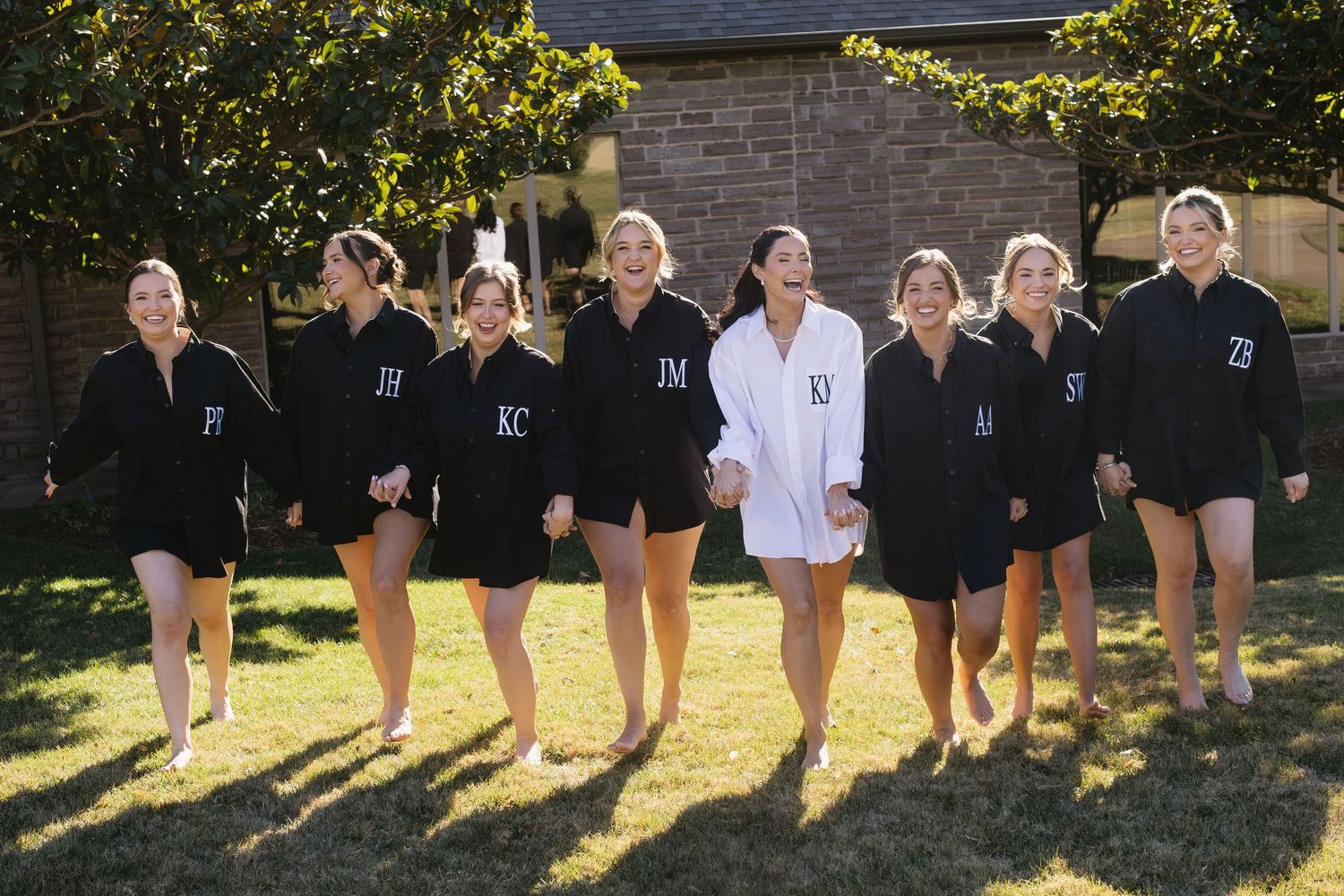 Group wearing matching black robes with one person in white standing together outdoors.