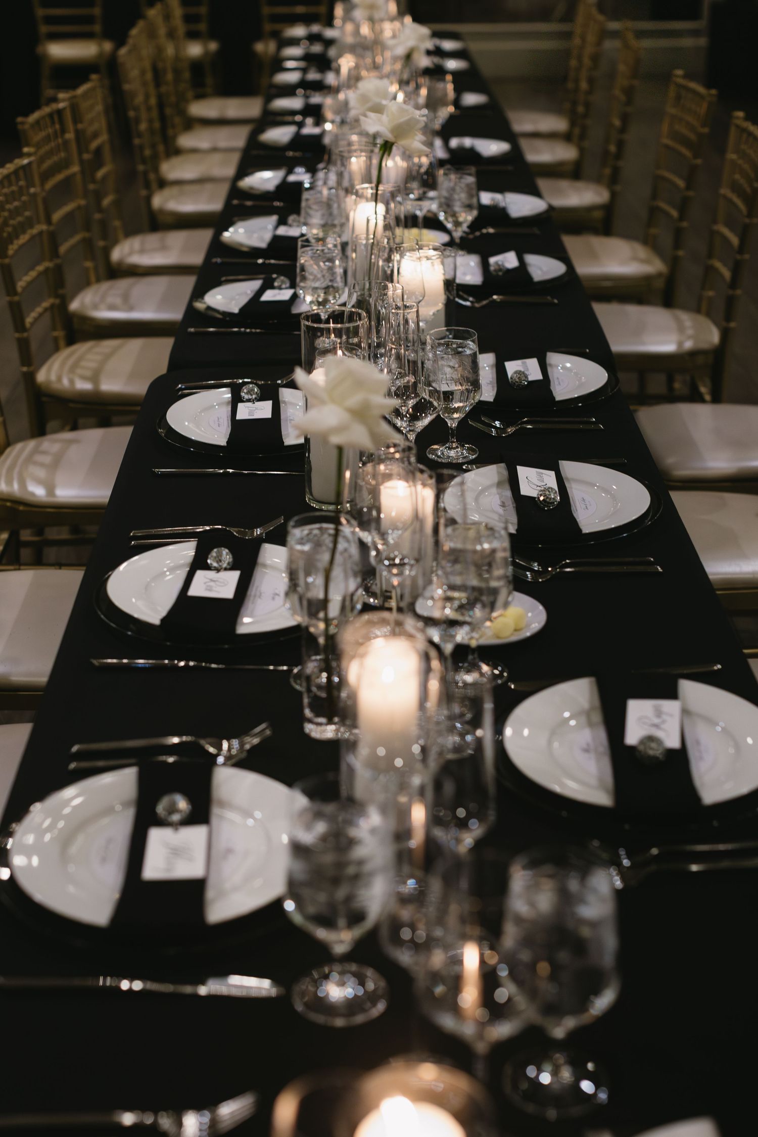 Elegant wedding reception table setting with black linens and crystal centerpieces.