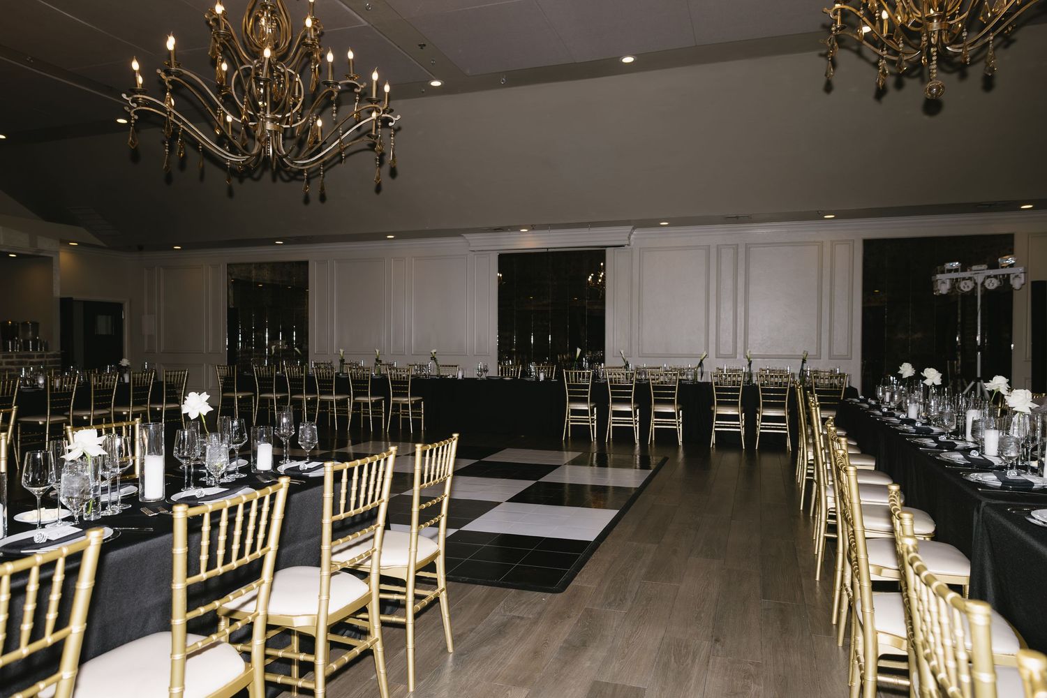 Large empty wedding venue with rows of gold chairs and dramatic lighting.