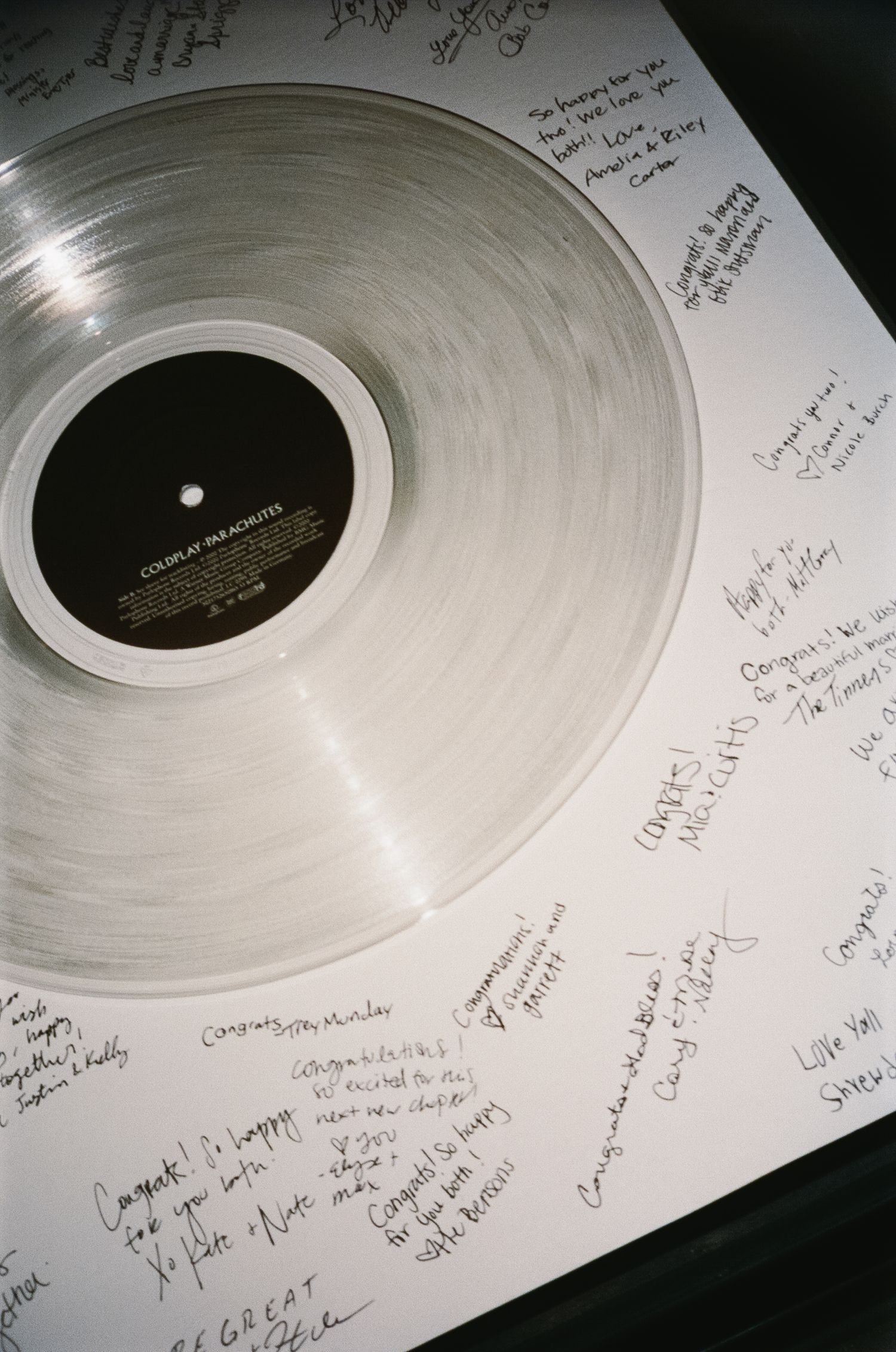 White vinyl record with handwritten signatures and messages around the center label.