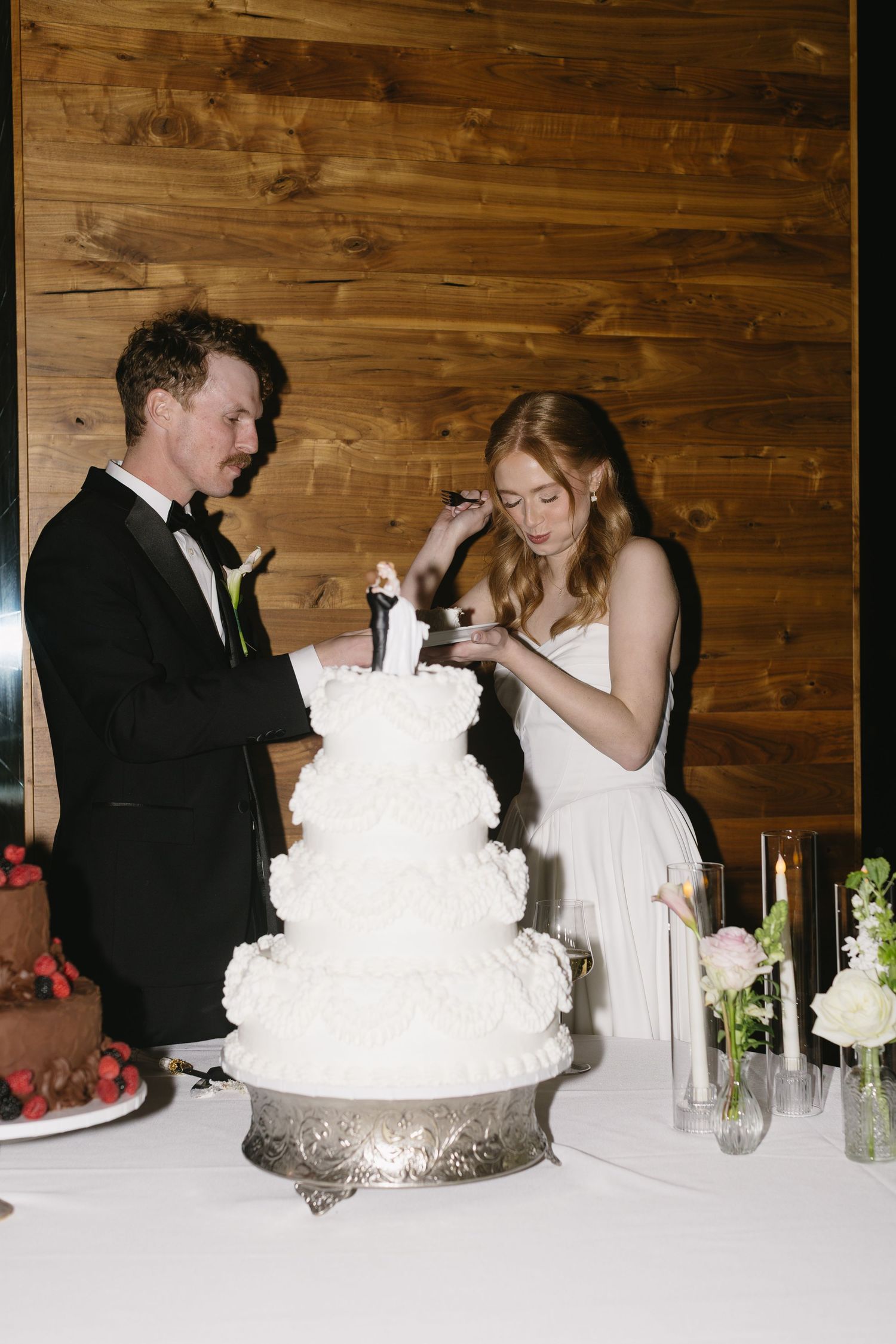 Wedding couple cuts their elegant white tiered cake at reception.