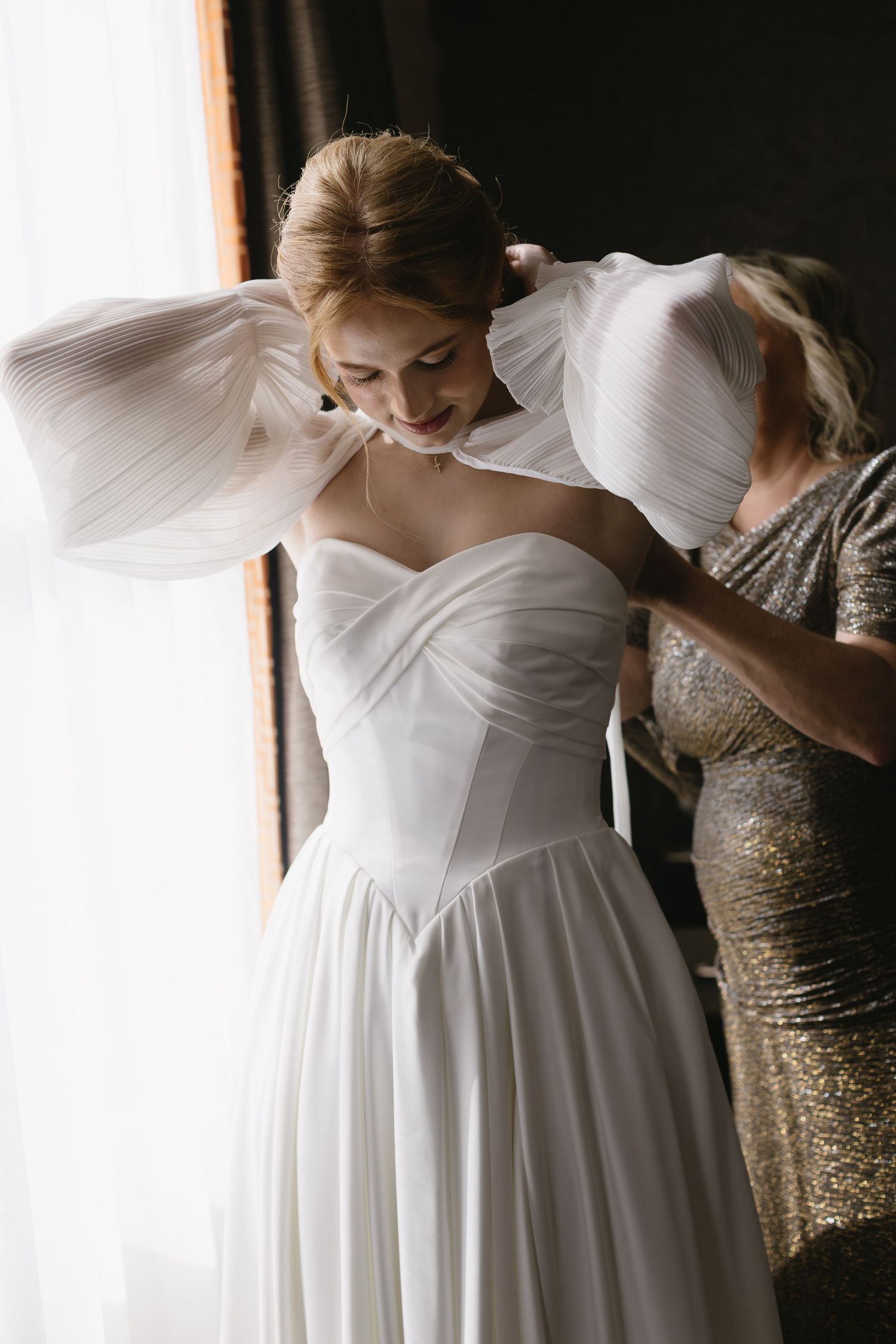 Wedding dress preparation showing details of white sweetheart neckline and flowing skirt.
