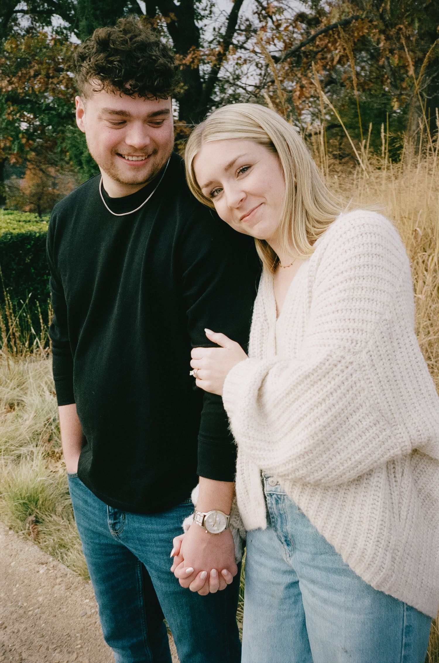Couple holding hands outdoors in matching casual wear during fall season.