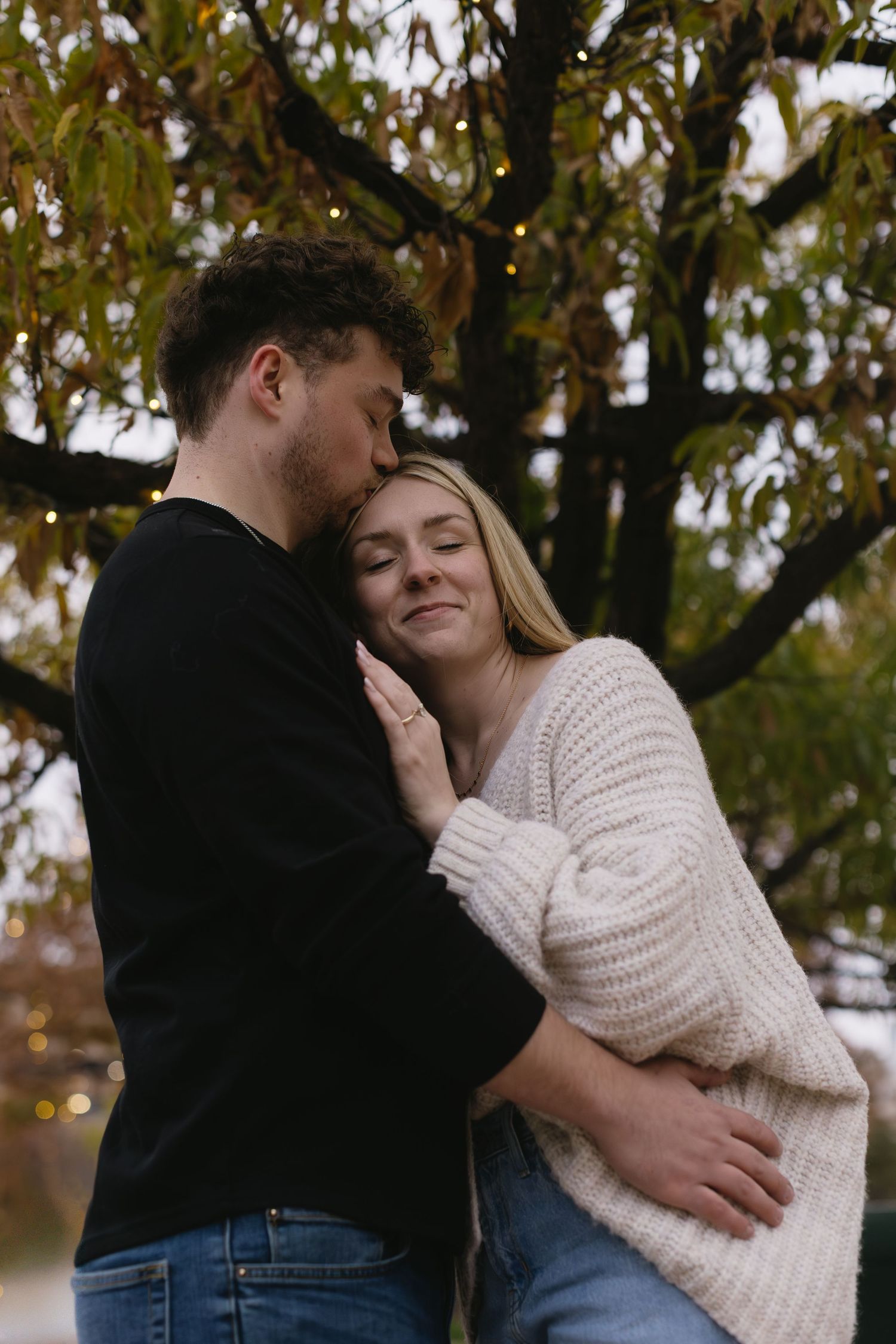 A tender embrace captured between a couple under autumn trees.