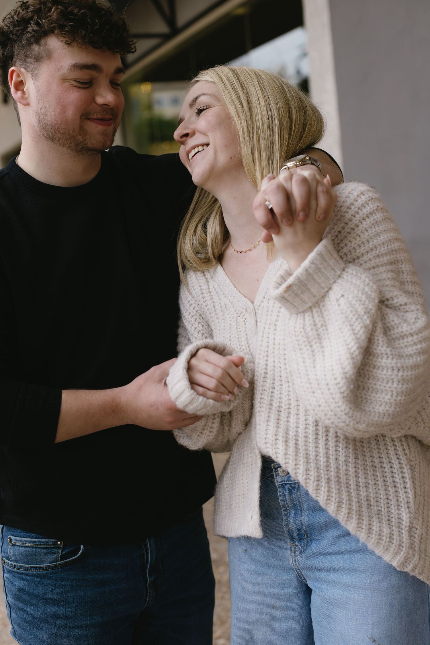 A sweet candid moment between a couple sharing laughter while holding hands.