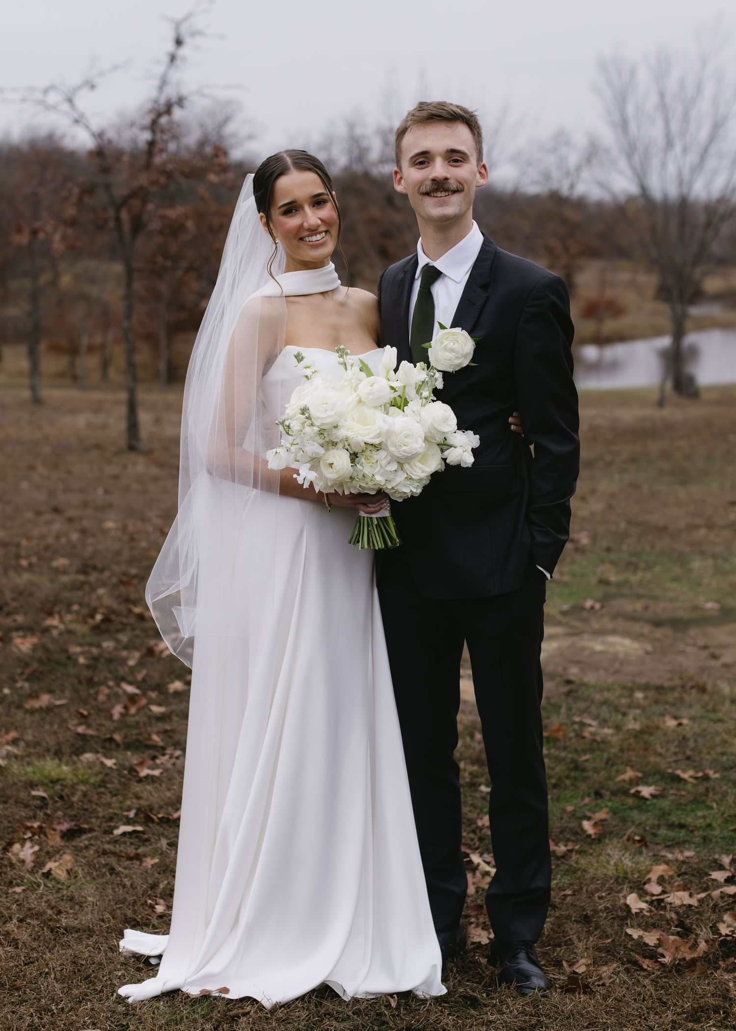 Newlyweds pose for portraits in an autumn landscape with fallen leaves.