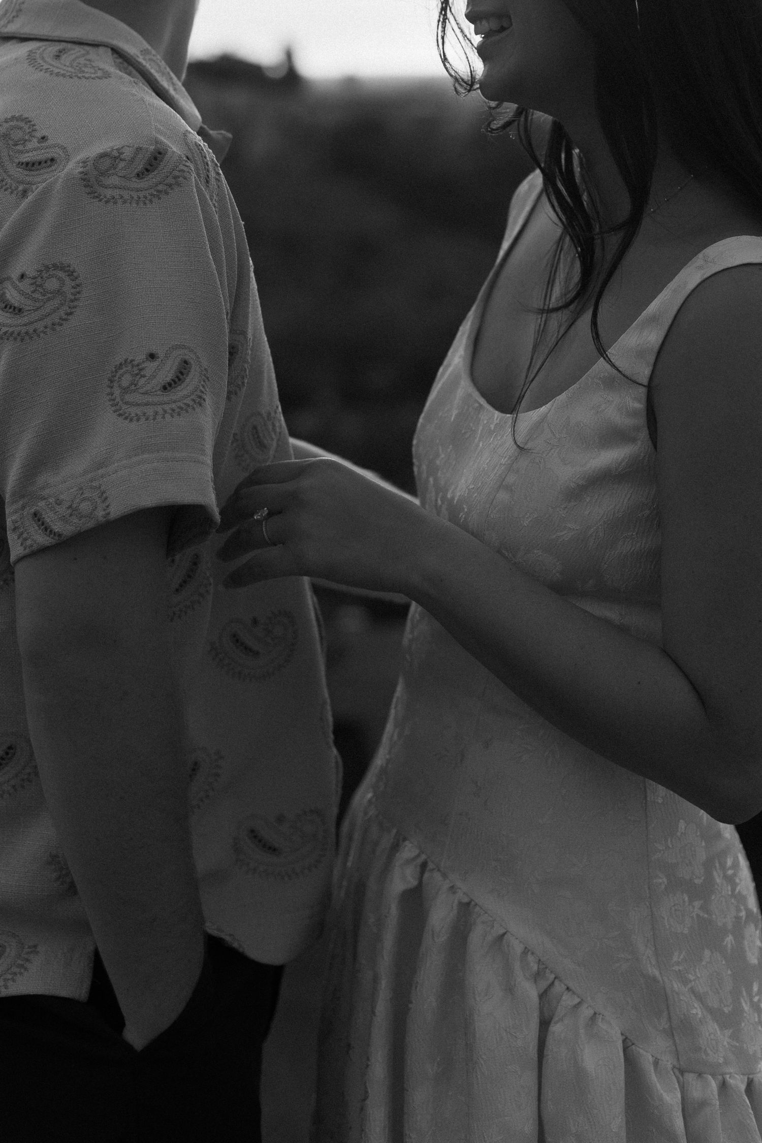 Black and white portrait of a couple embracing outdoors at dusk.