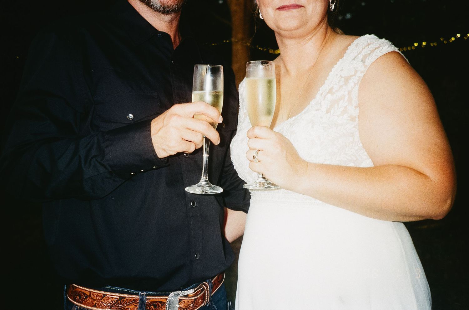 People raising champagne glasses in celebration at a dark formal event.