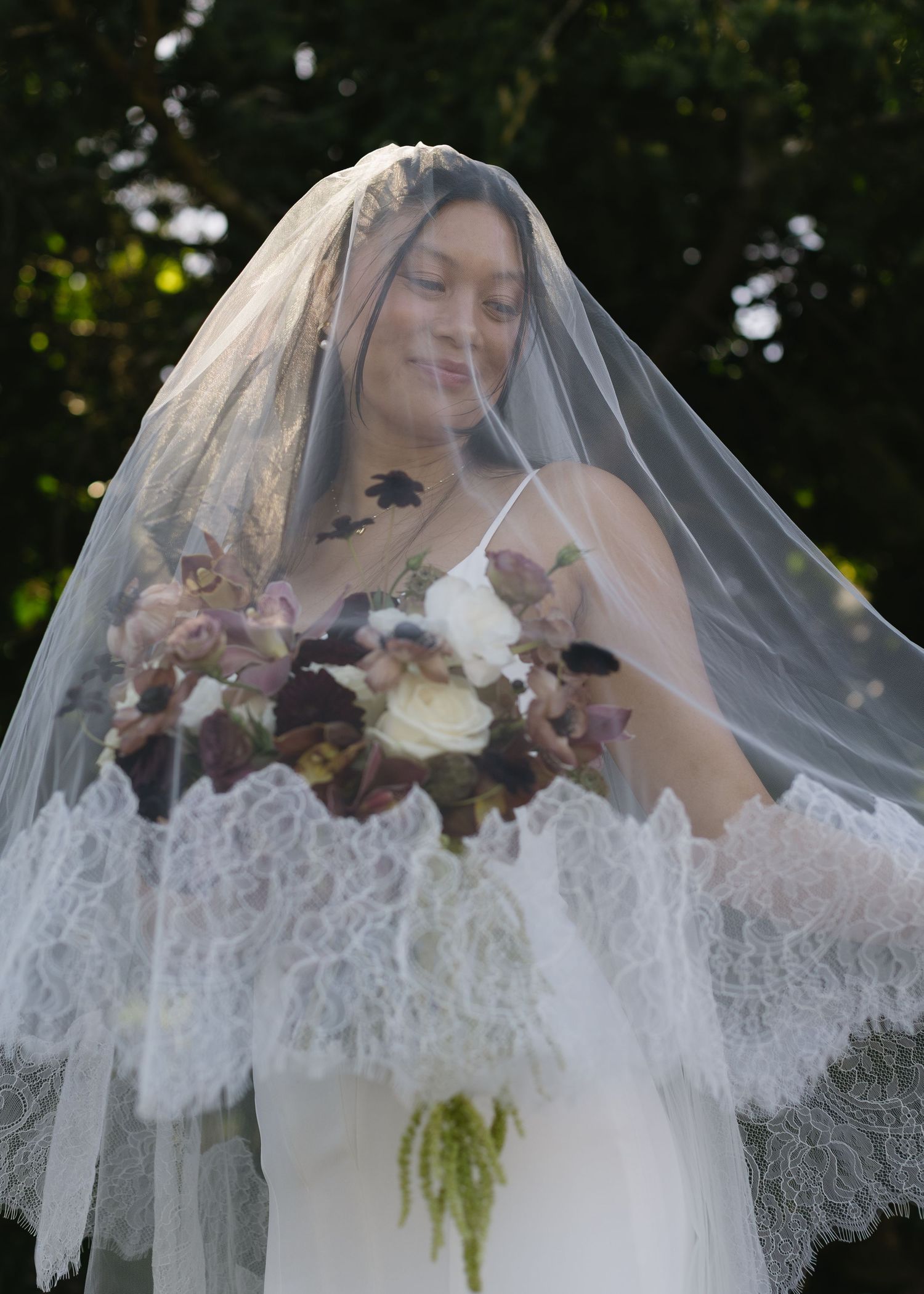 Delicate lace veil with floral details drapes elegantly in outdoor garden setting.