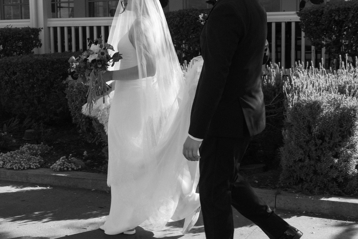 Black and white wedding photos showing a couple walking together outdoors in formal attire.