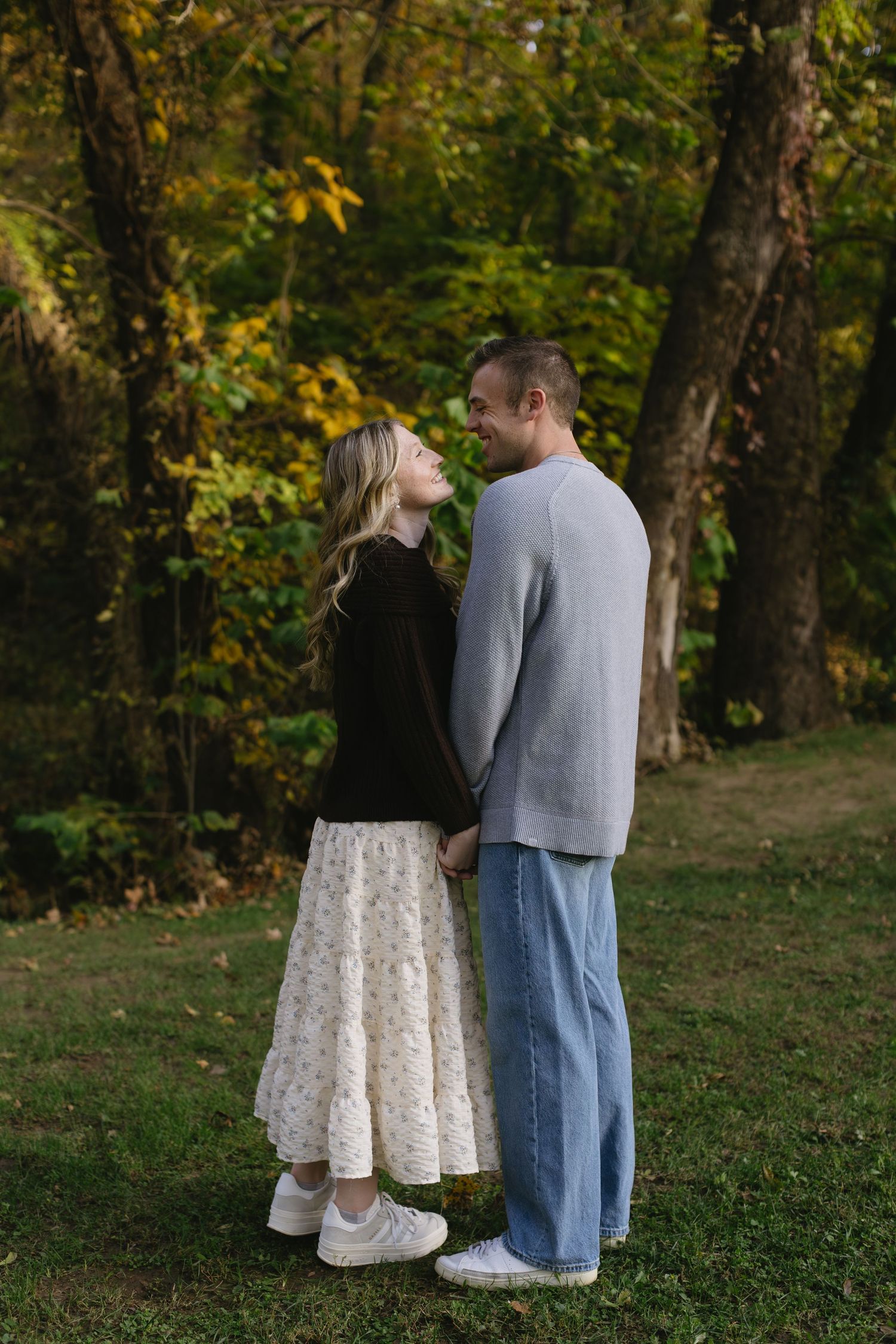 A romantic couple sharing an intimate moment among autumn trees in a park setting.