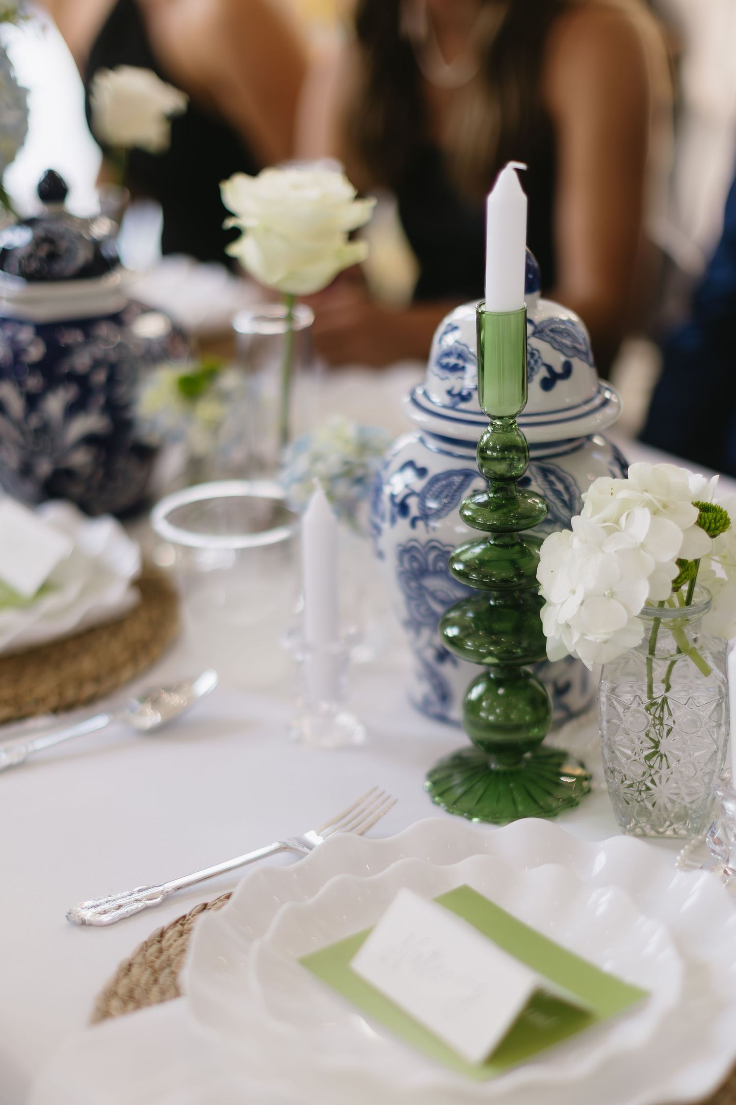 Elegant wedding table setting with blue and white china, green accents, and white floral centerpieces.