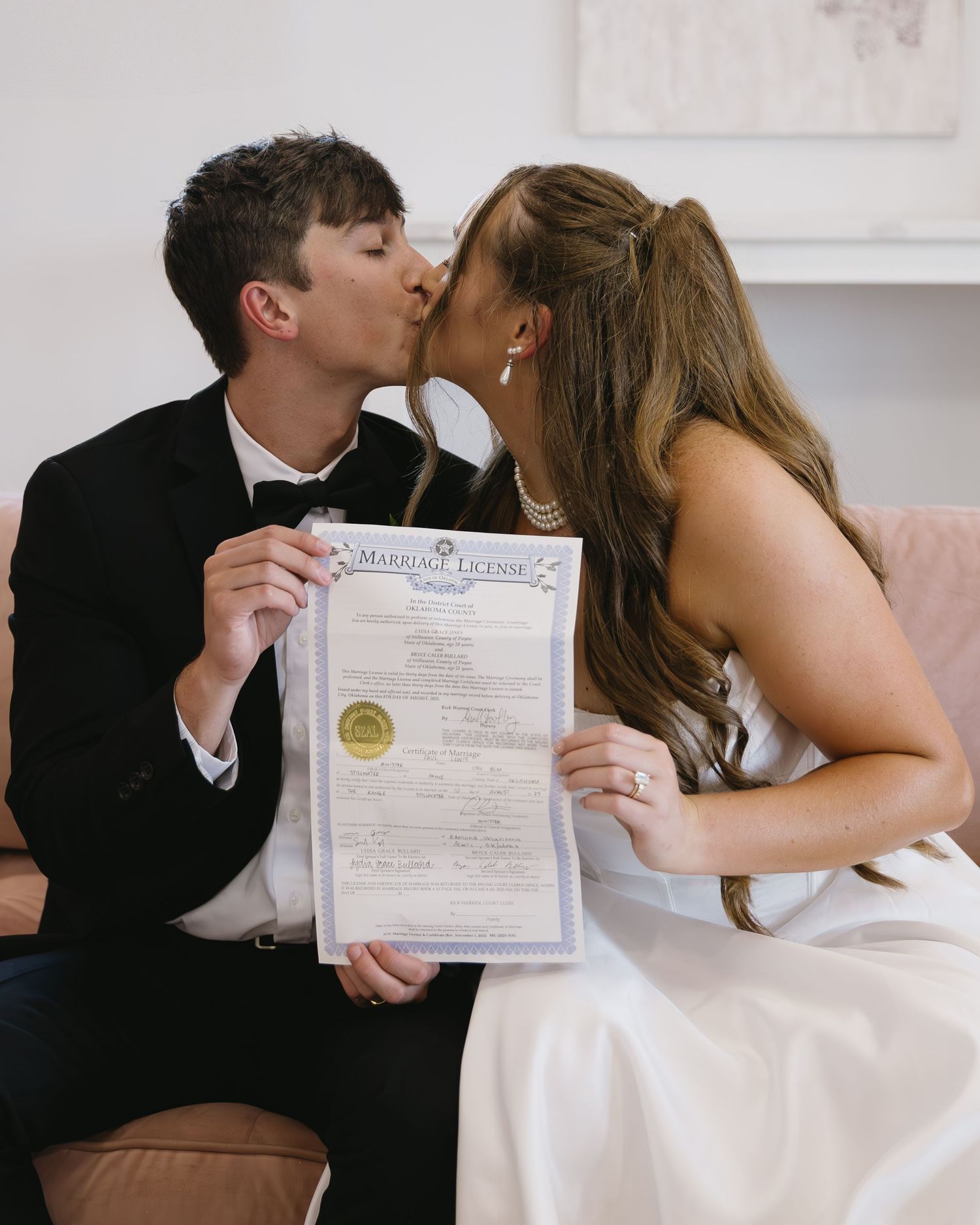 Wedding couple displaying marriage certificate while sharing intimate moment.