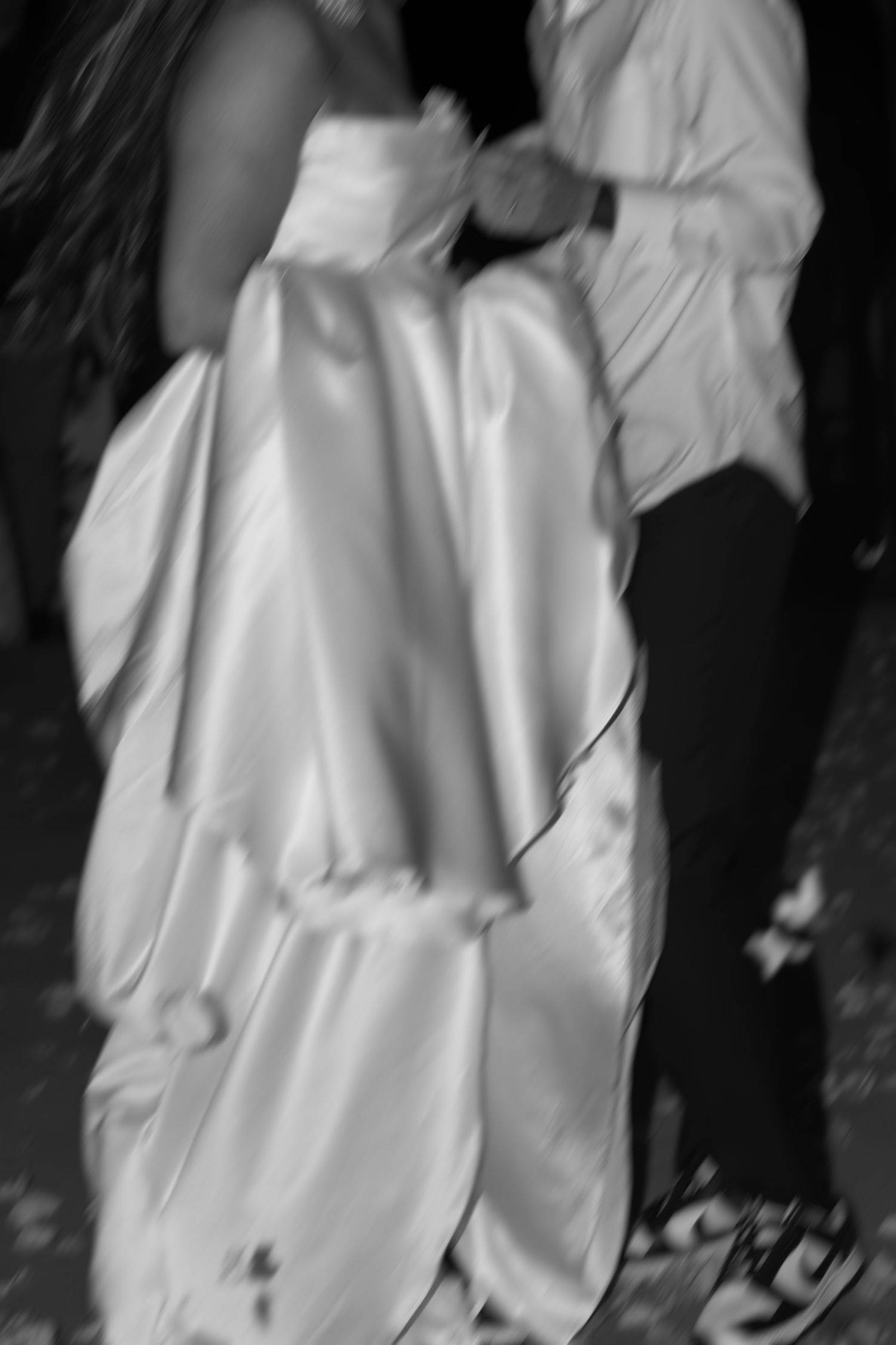 Close-up details of flowing white wedding dress fabric in dramatic lighting.