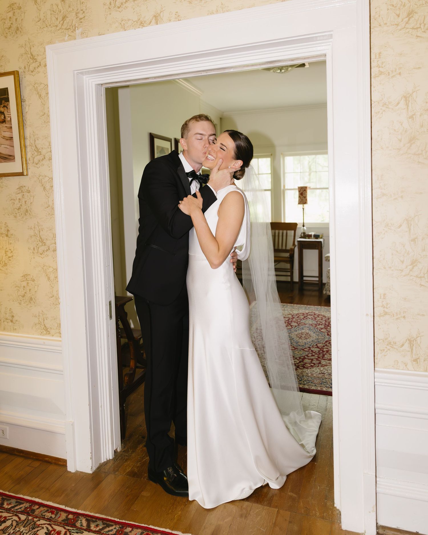 Bride in elegant white dress dances with her partner through the grand doorway of an upscale venue.