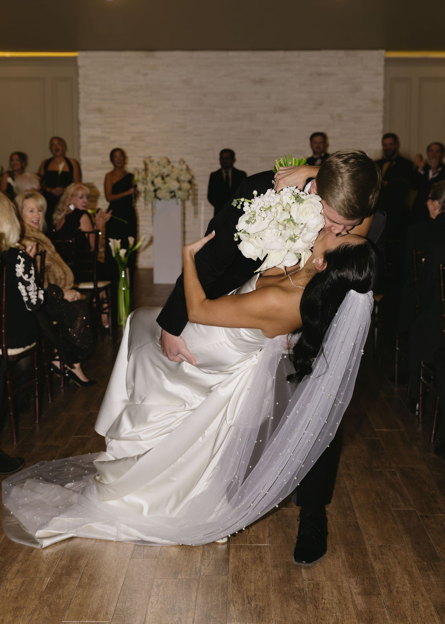 Dramatic wedding dance dip on wooden floor during reception.