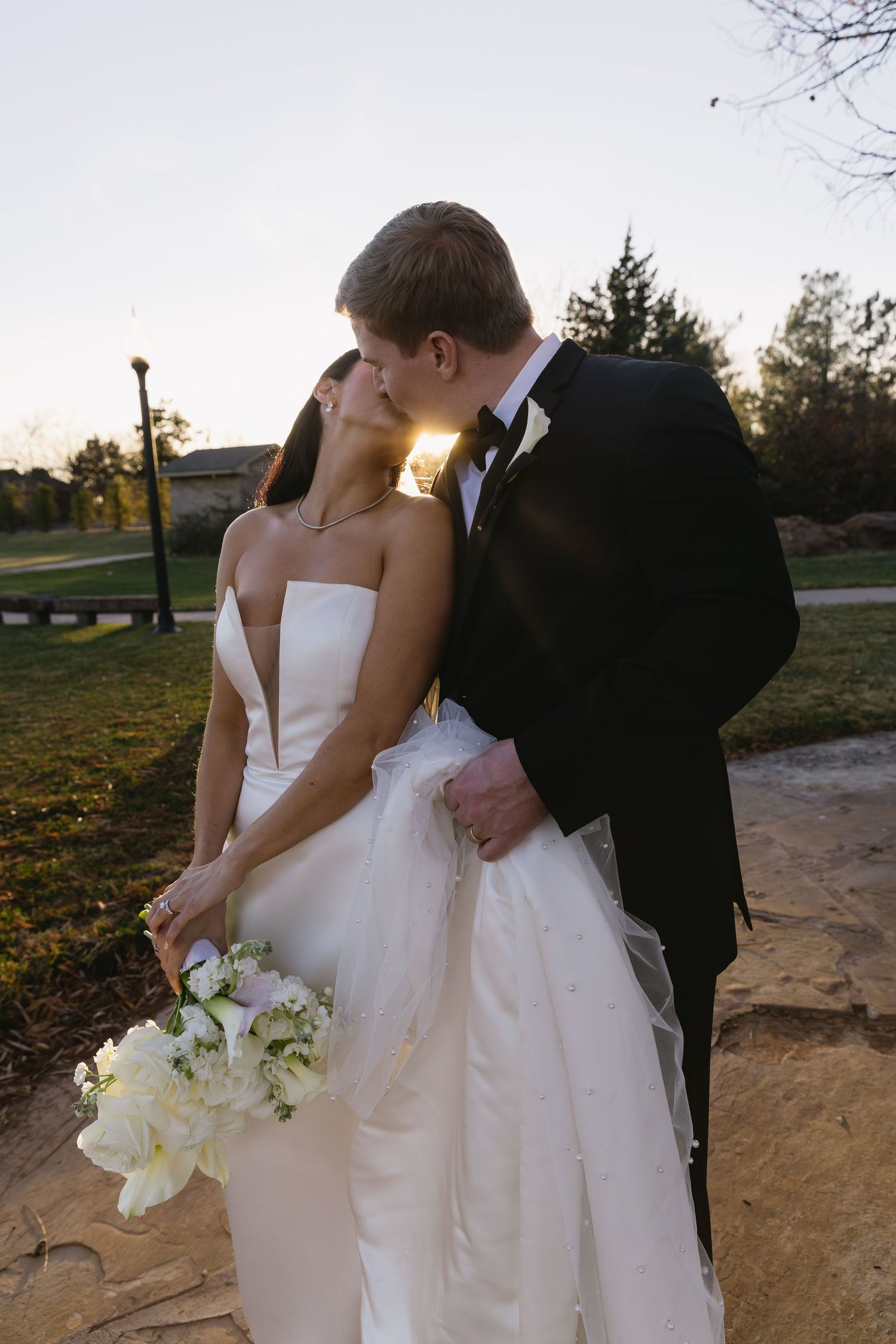 Wedding couple embraces during golden hour sunset in an outdoor setting.