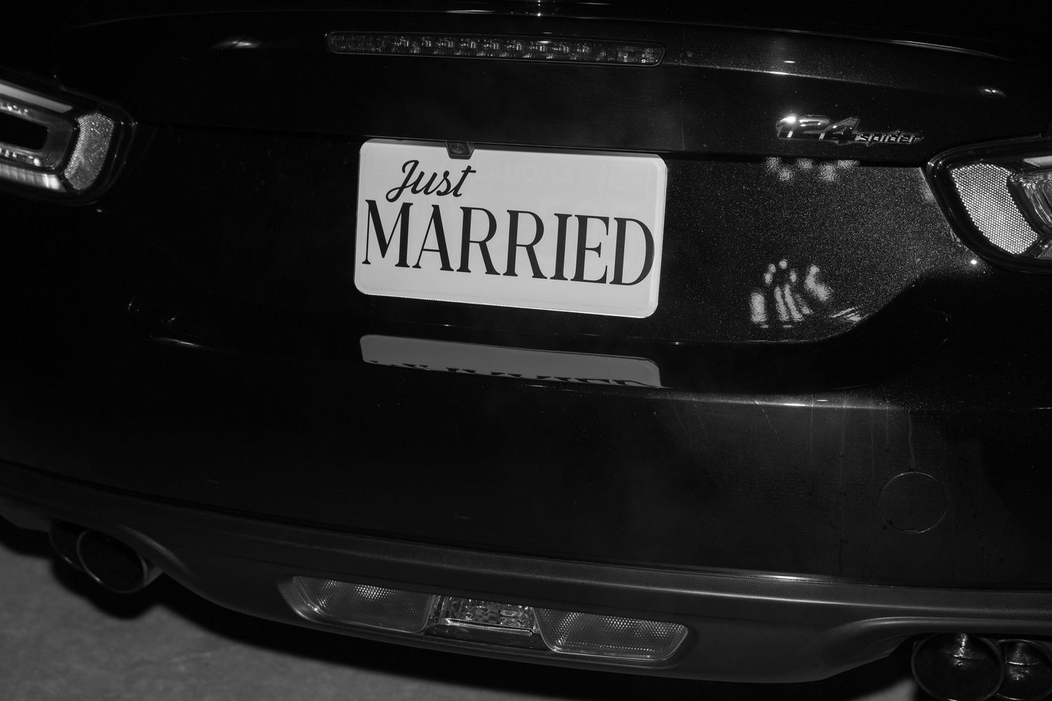 Black car decorated with 'MARRIED' text for wedding getaway.