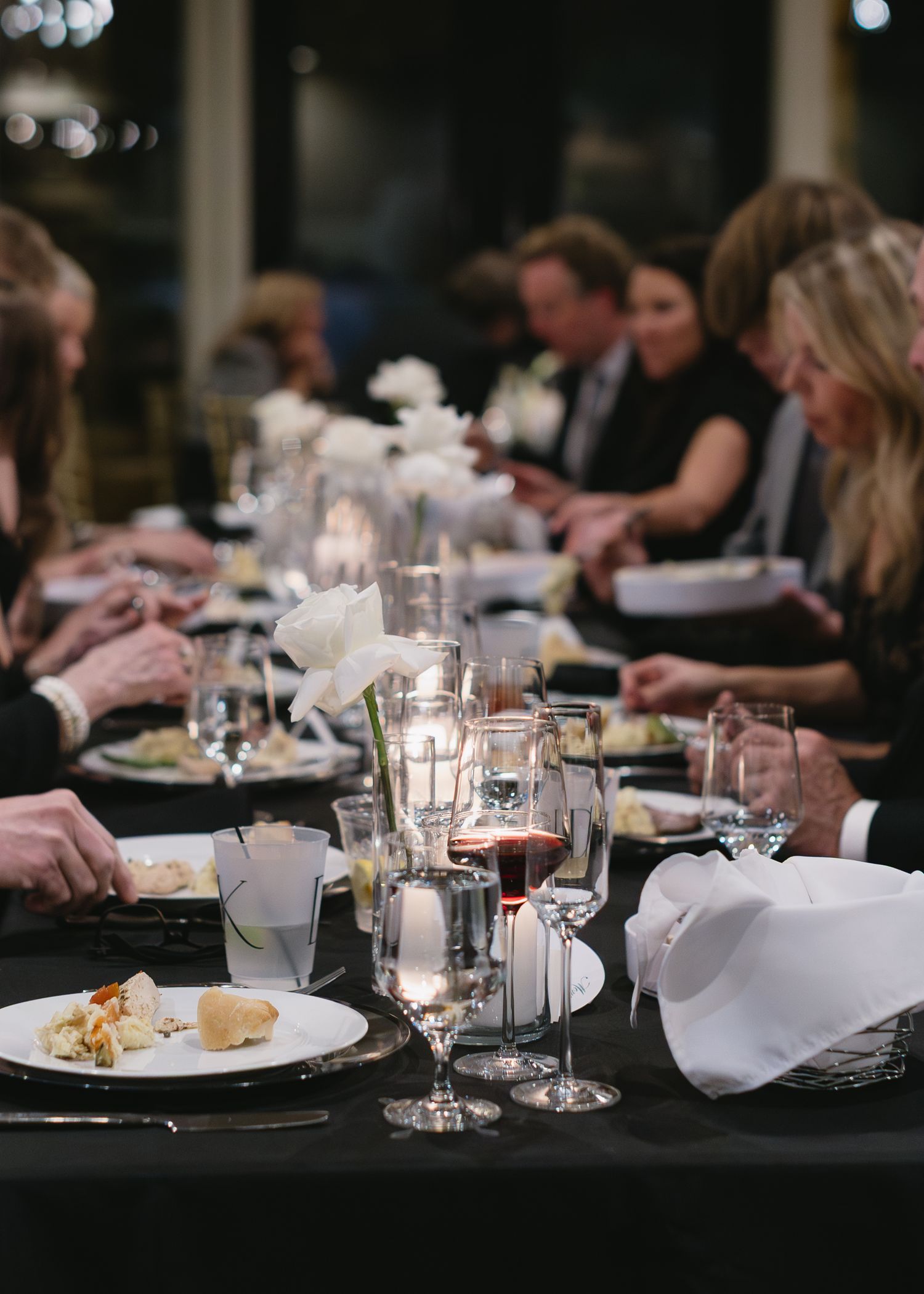 Formal dinner table setting with glowing candles, white napkins, and elegant place settings.
