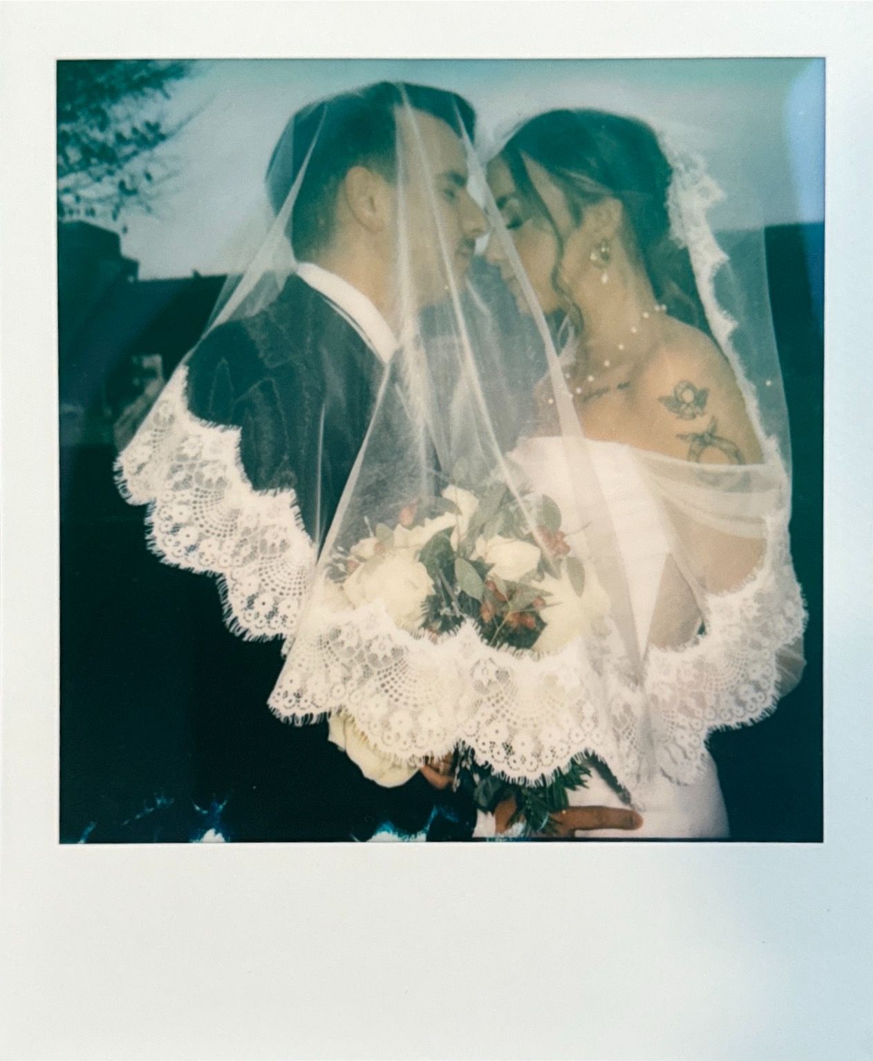 Romantic polaroid-style wedding photo through lace veil.