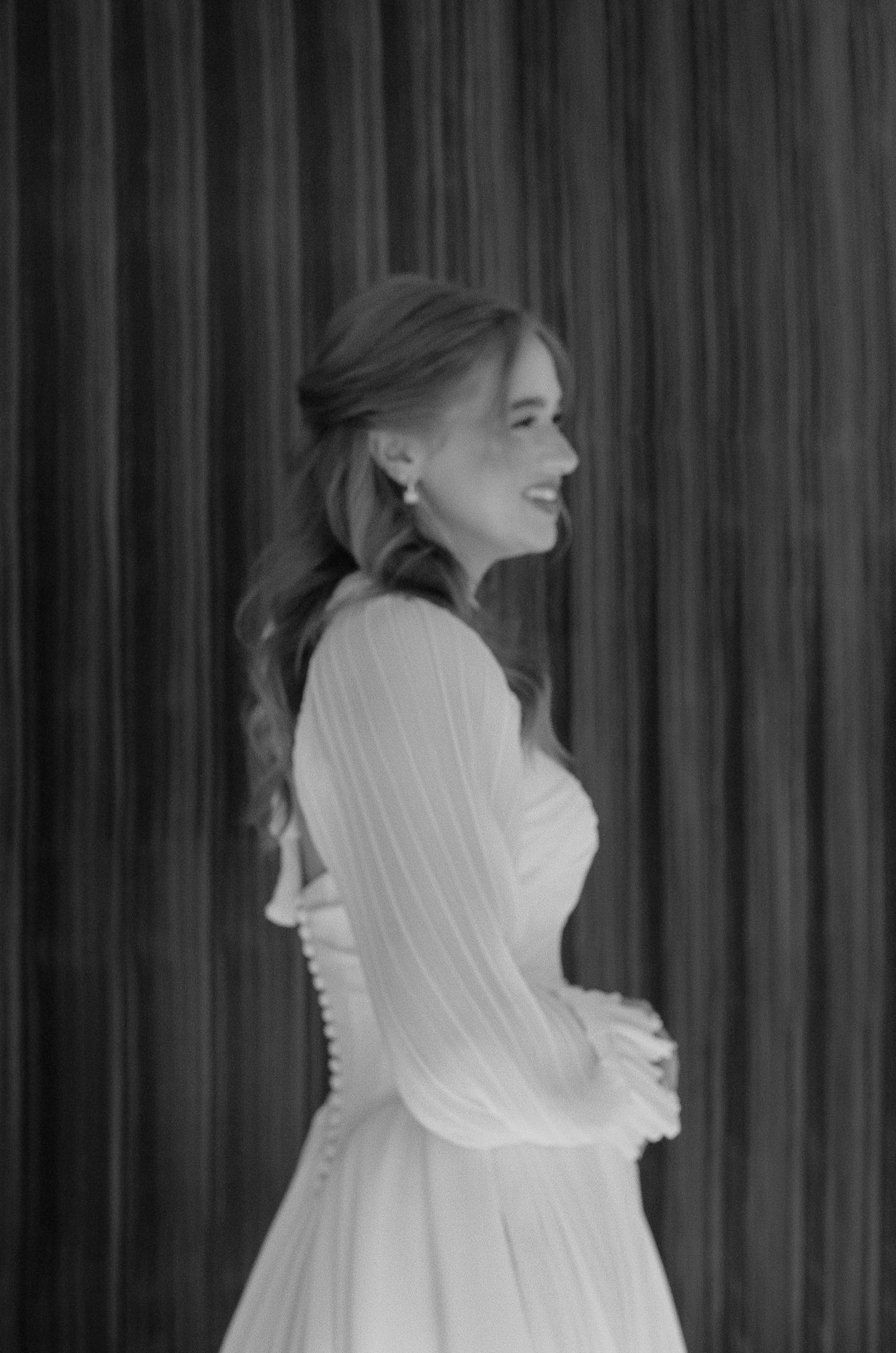 Artistic black and white series capturing bride's profile with flowing veil against dark backdrop.