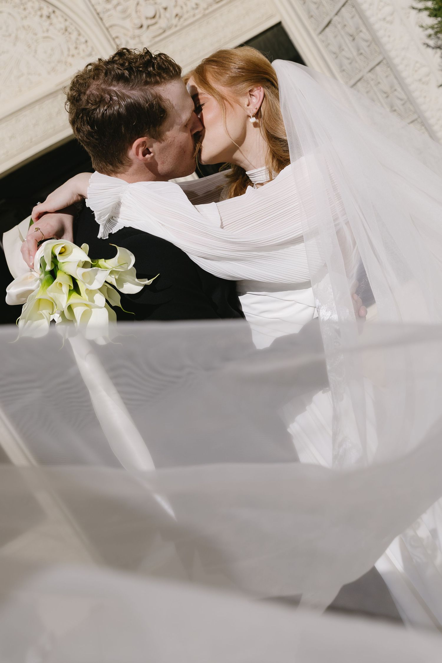 A romantic wedding couple embraces under a flowing white veil in an artistic series of photos.
