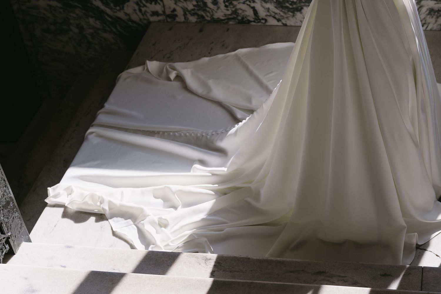 Wedding dress details with flowing fabric captured in dramatic lighting.