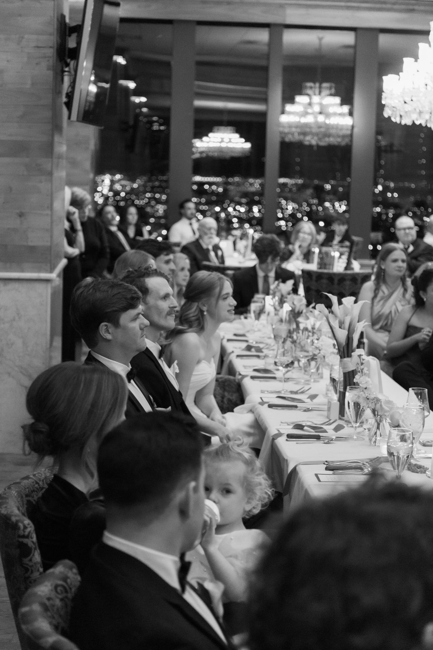 Wedding reception dining room with guests seated at elegant tables.