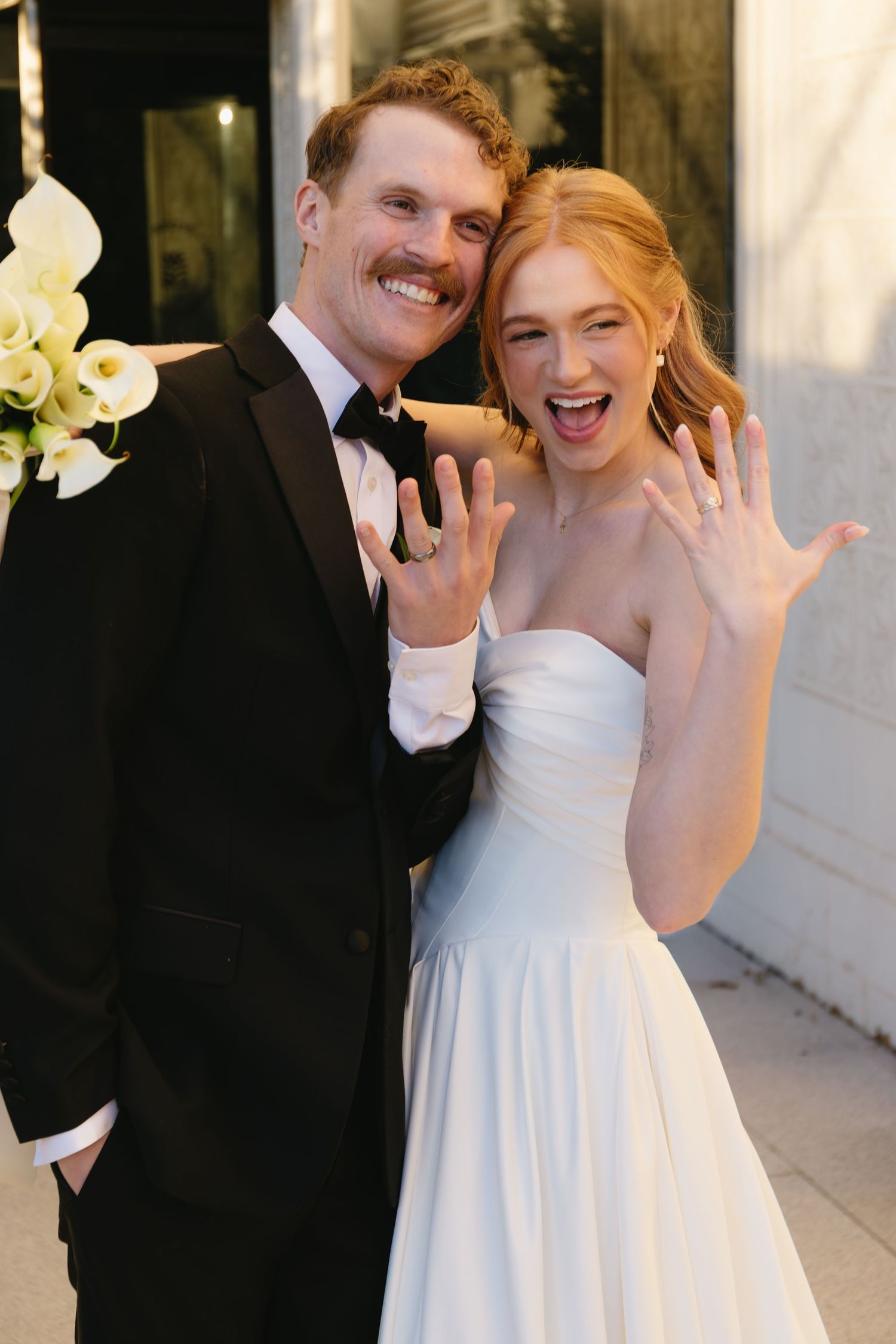 Joyful wedding couple showing excitement and happiness outside venue.