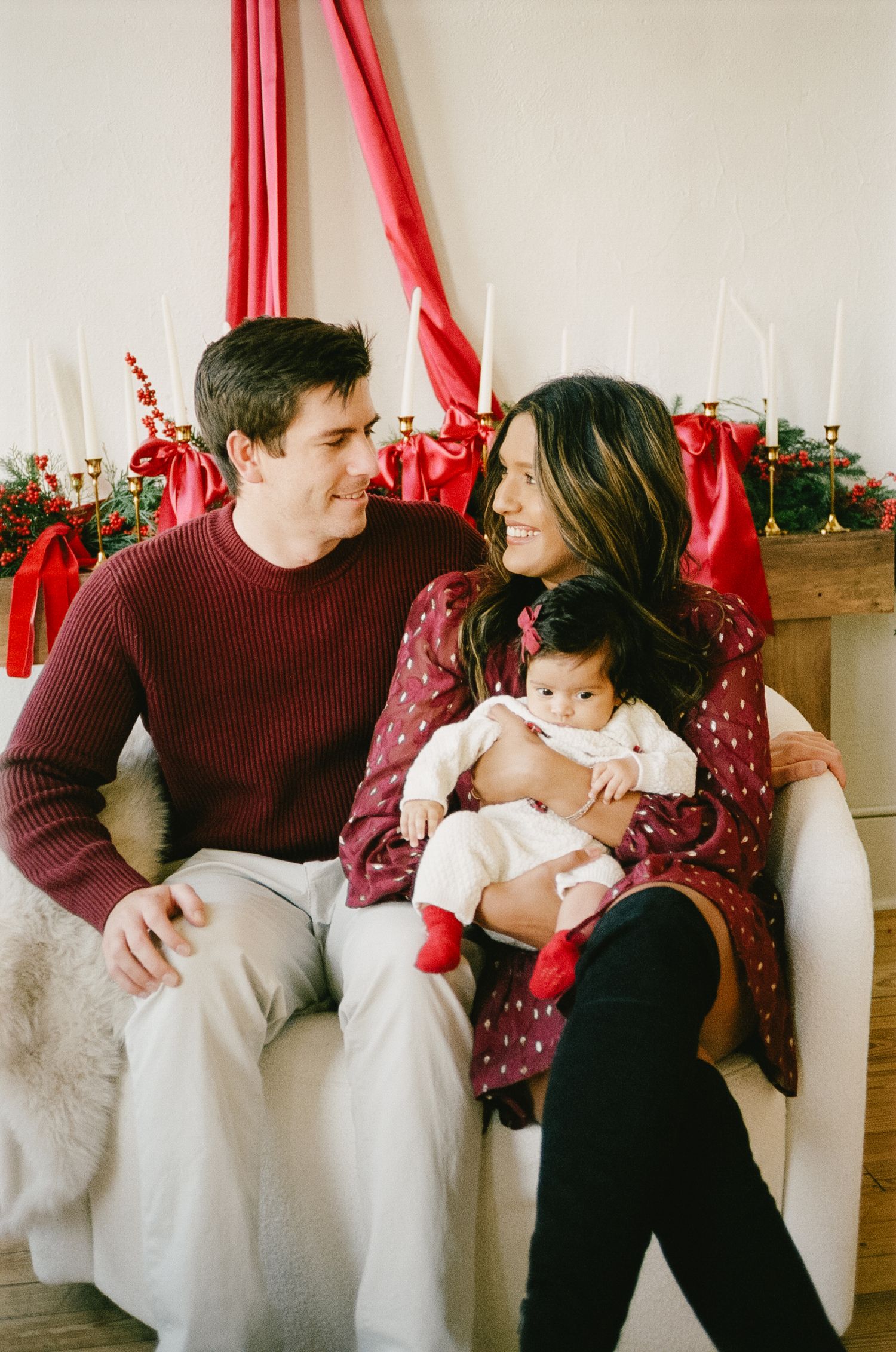 Cozy holiday scene with burgundy sweater and polka dot dress against white and red Christmas decorations.