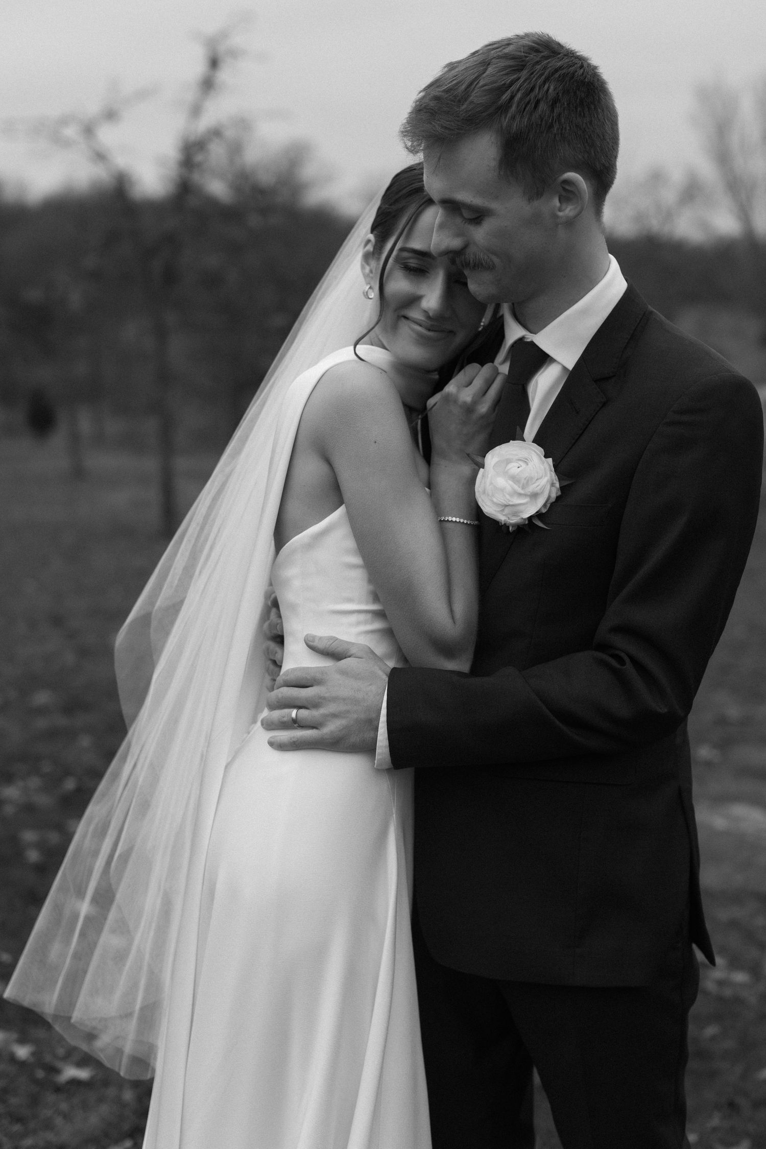 Black and white wedding portraits capturing intimate moments between bride and groom in outdoor setting.