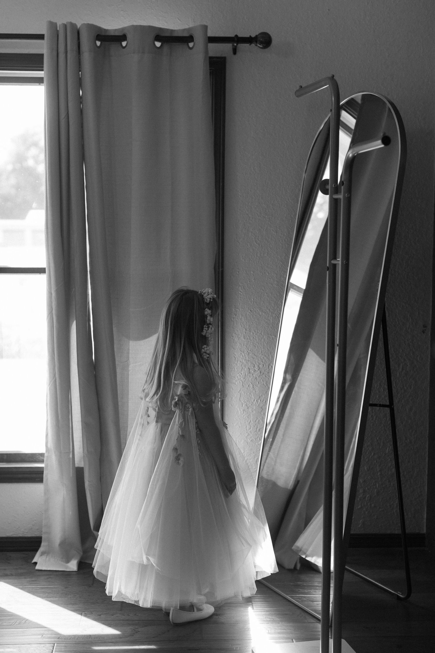 Black and white photos of a wedding dress hanging in a sunlit room with dramatic lighting and shadows.