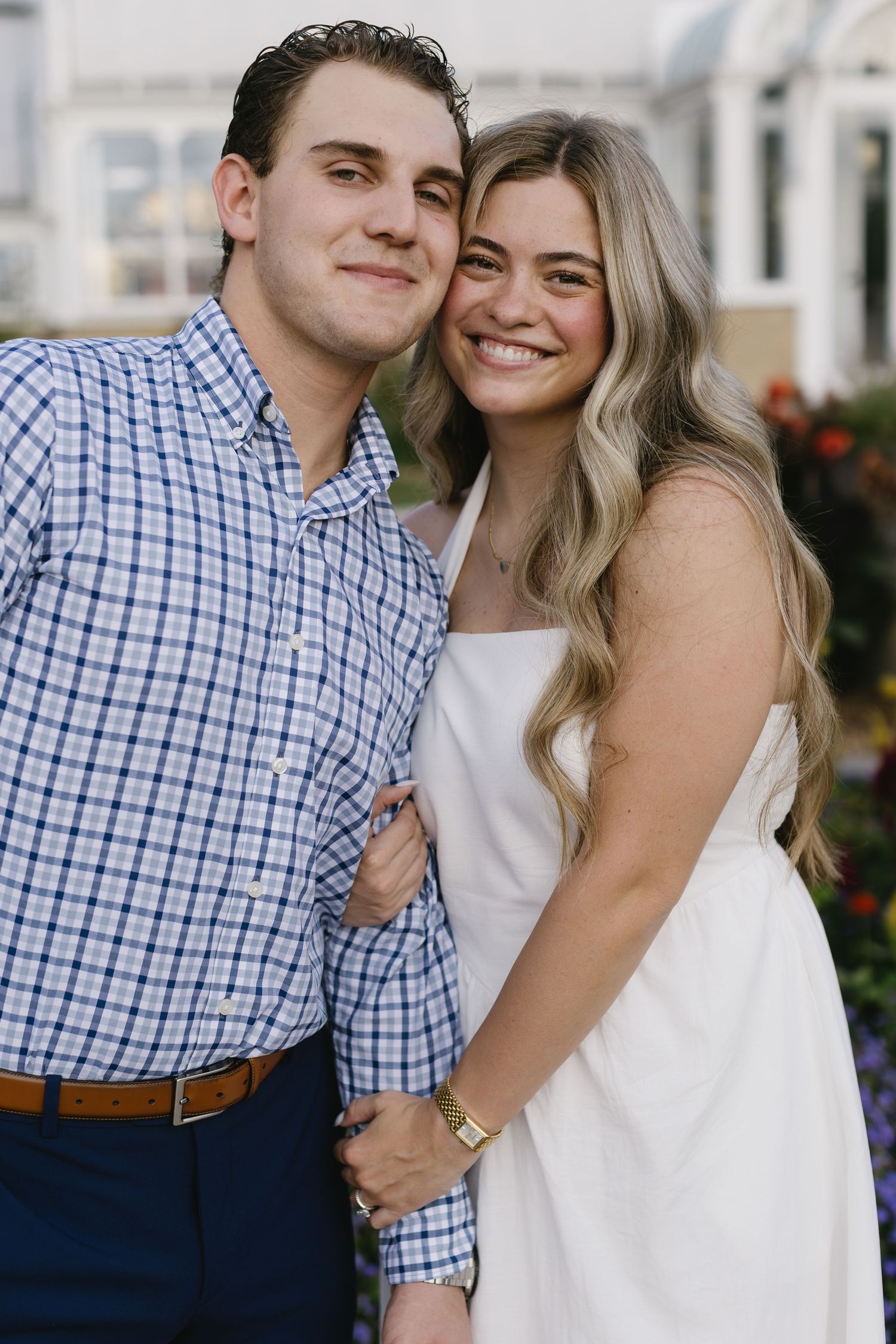 A close-up portrait of a couple embracing, with one in a checkered blue shirt and the other in white.