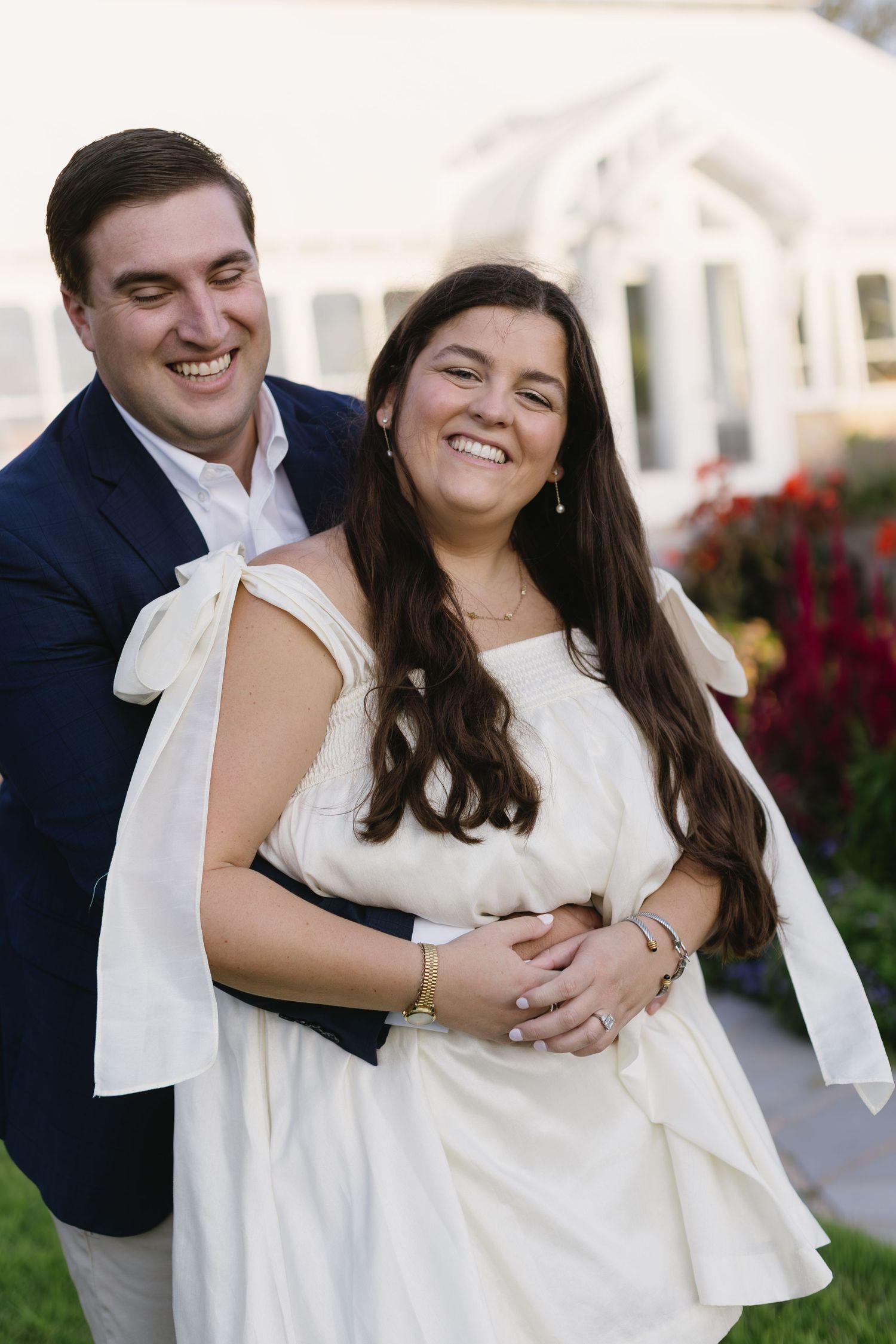 Joyful couple embracing and laughing during an outdoor portrait session in formal attire.
