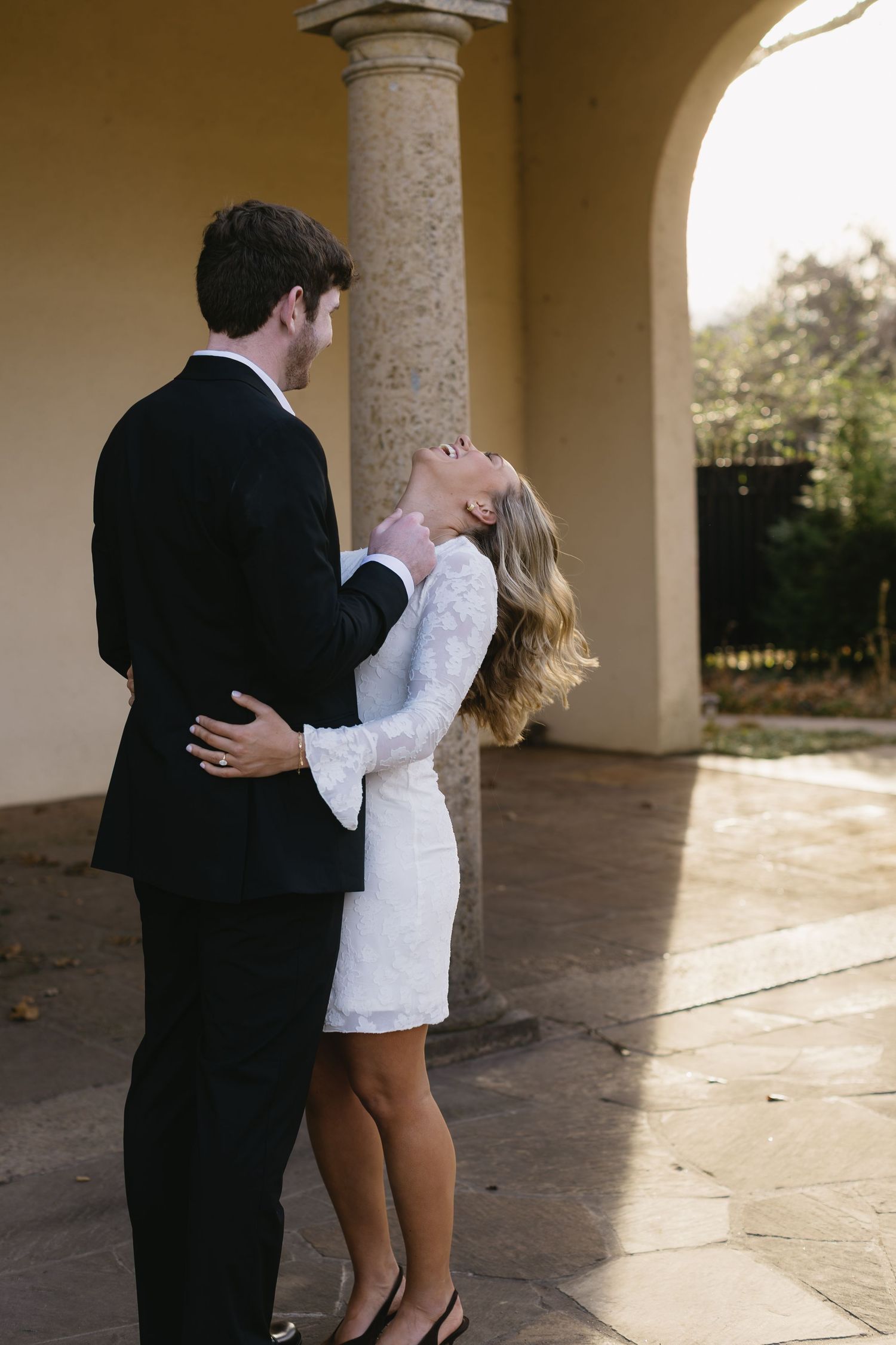 A couple shares an intimate moment under stone archways during a romantic photoshoot.