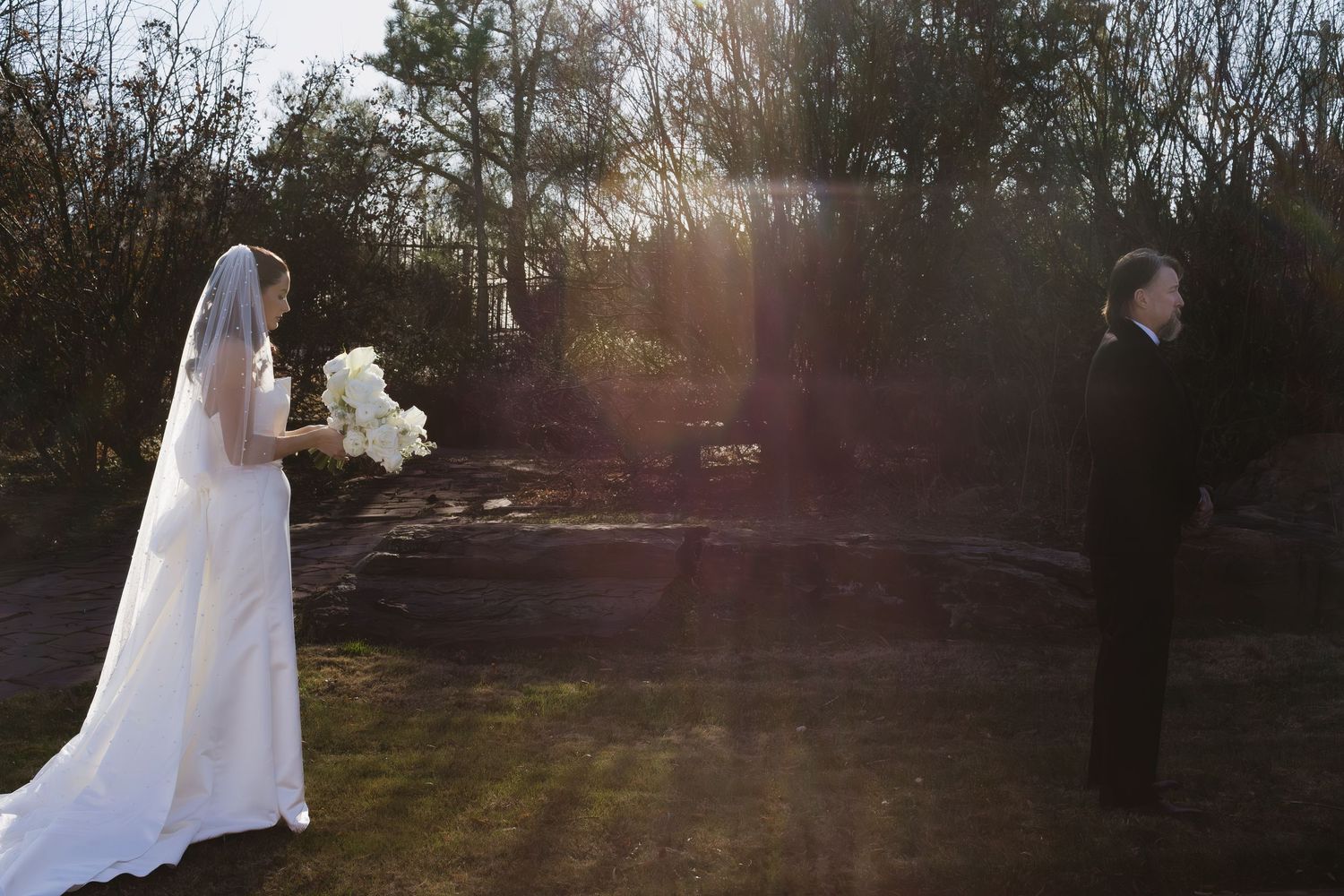 Ethereal outdoor wedding photography with sunlight streaming through trees.