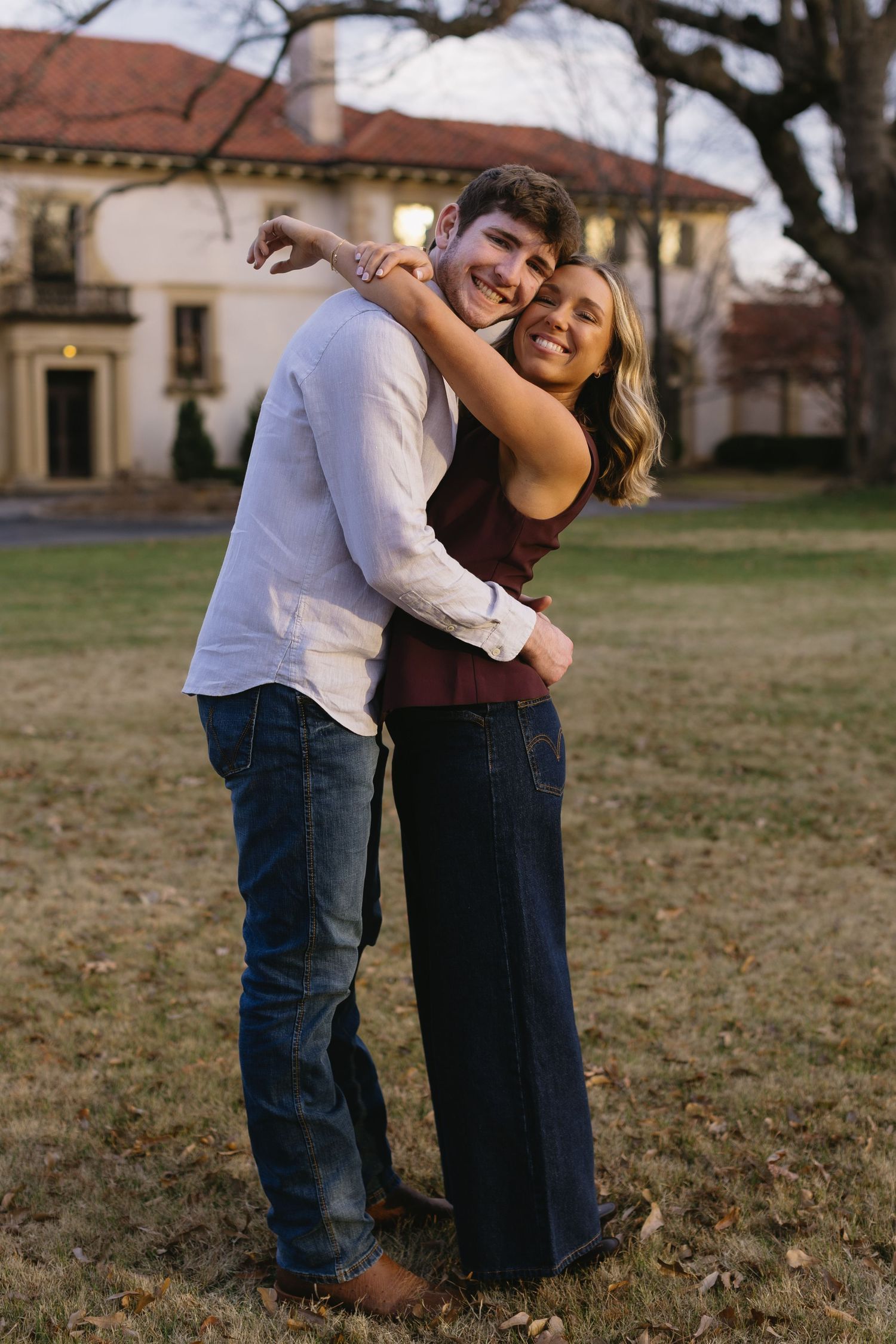 A joyful couple sharing laughter and embraces on a grassy field.