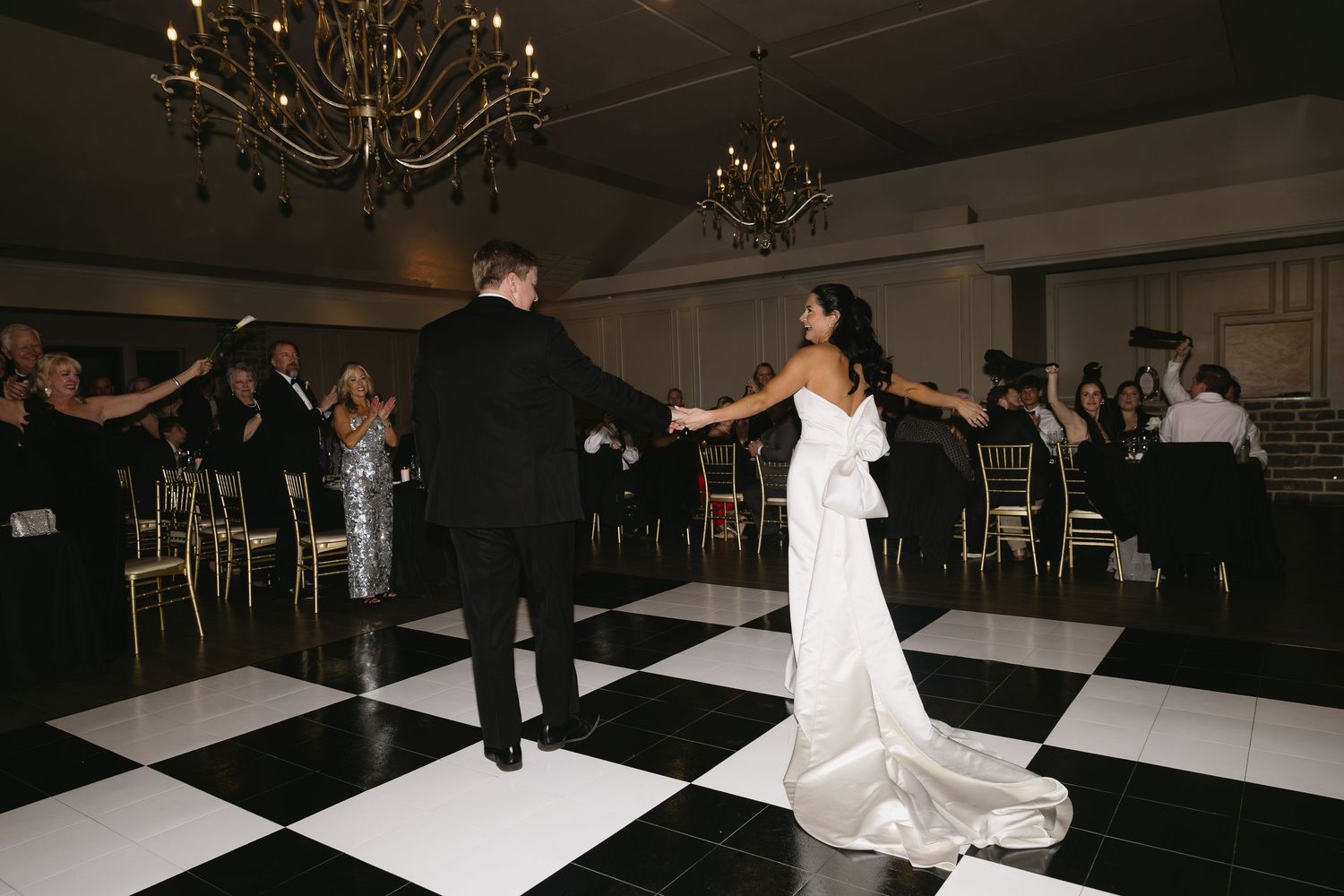 Wedding reception dance floor with black and white checkered pattern illuminated by overhead lighting.